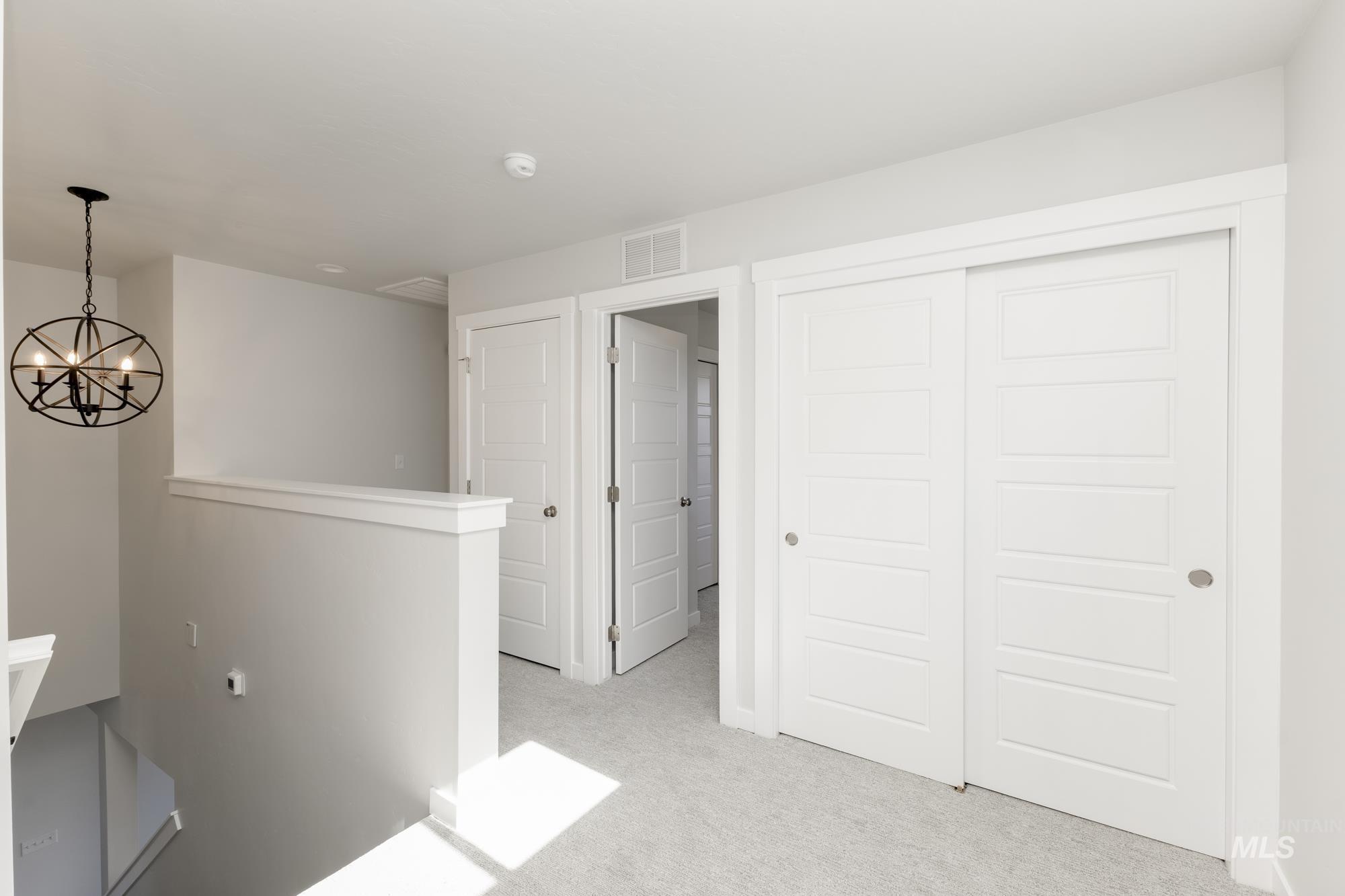 Hall featuring light carpet and a chandelier