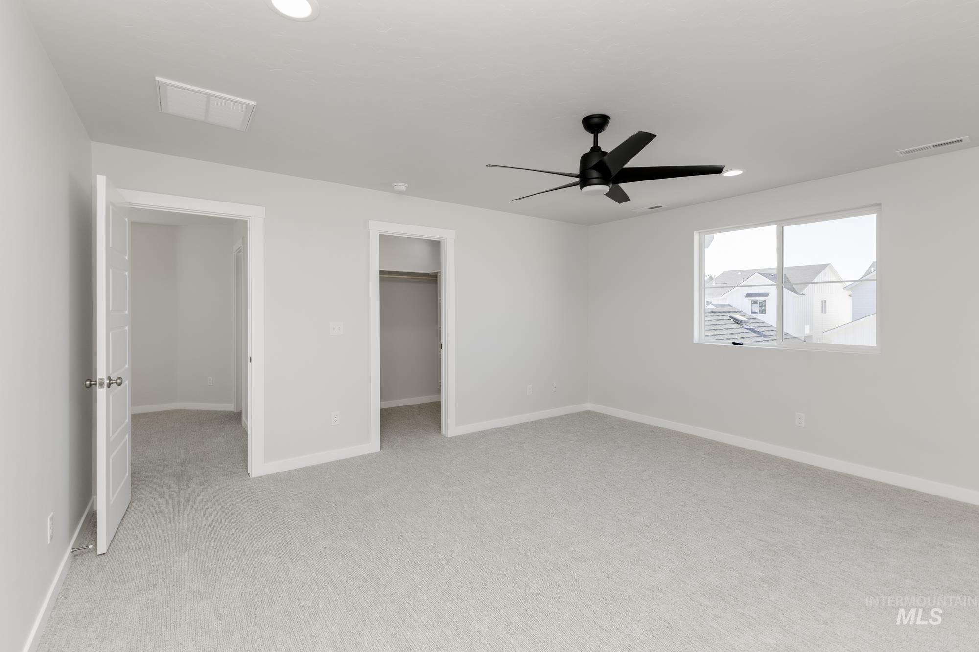 Unfurnished bedroom featuring a walk in closet, light colored carpet, a ceiling fan, and recessed lighting