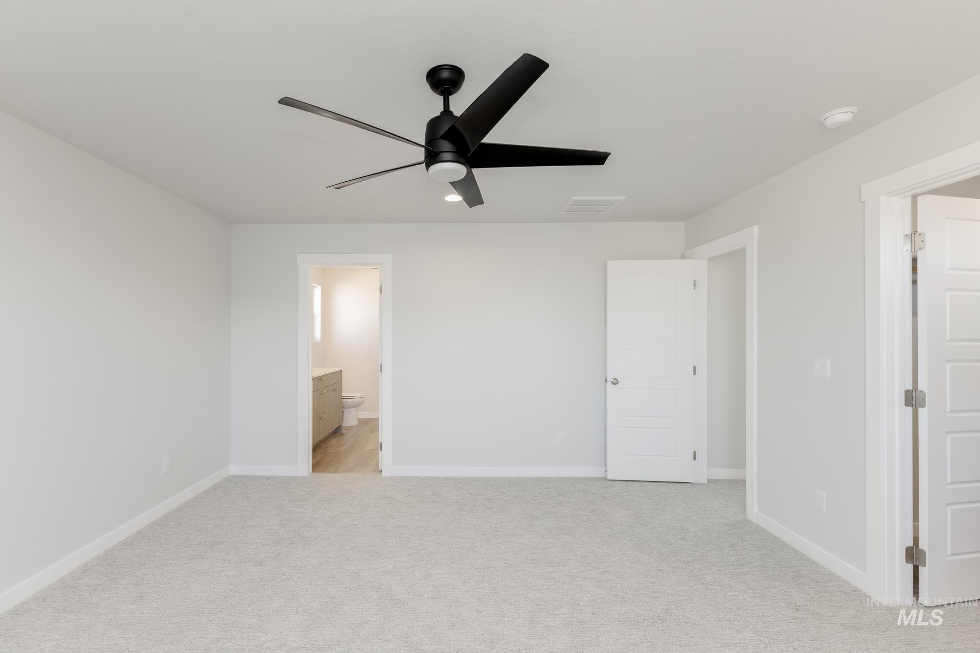 Unfurnished bedroom featuring light colored carpet, ceiling fan, and ensuite bathroom