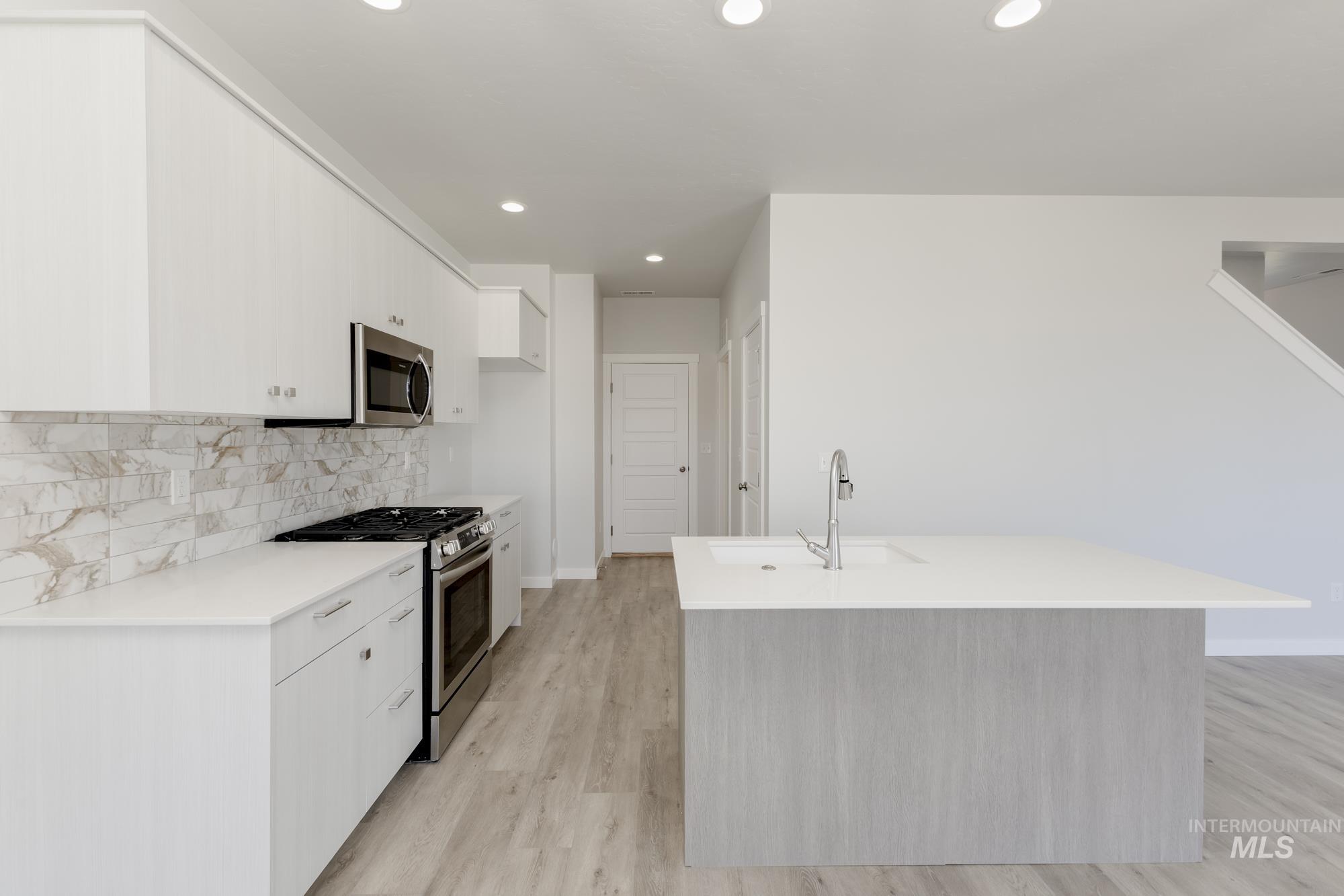 Kitchen with recessed lighting, appliances with stainless steel finishes, light wood-style floors, backsplash, and modern cabinets