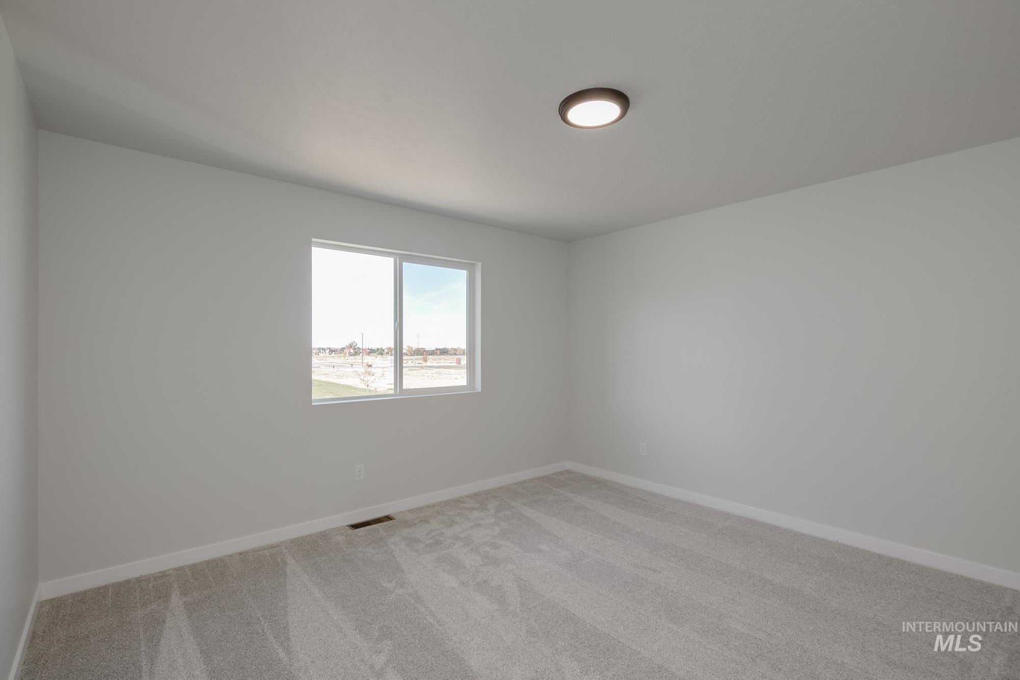 Empty room with light colored carpet and baseboards
