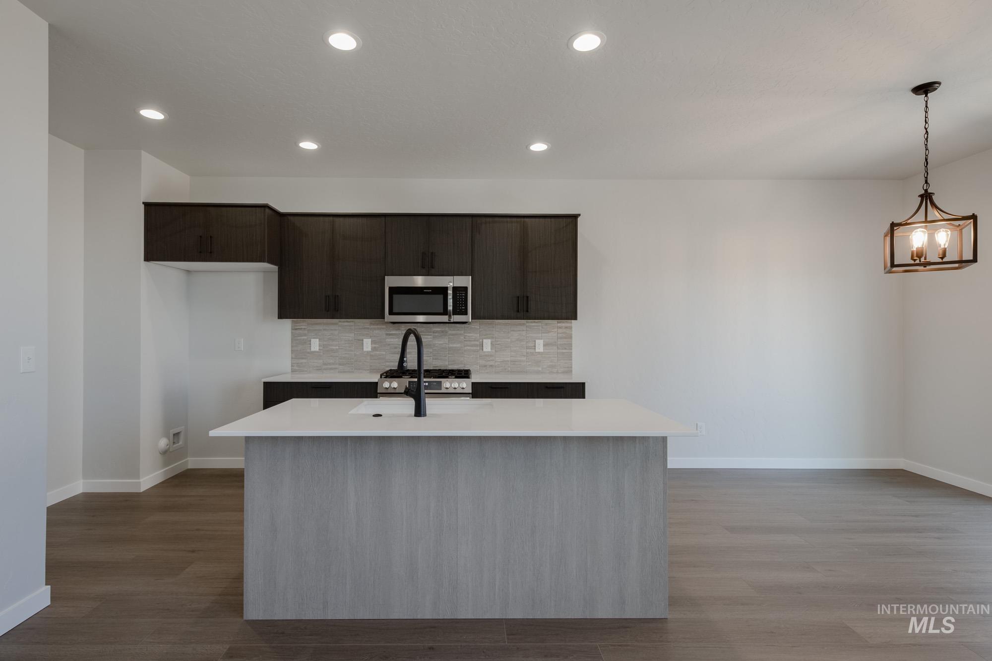 Kitchen featuring decorative backsplash, stainless steel appliances, recessed lighting, light wood-style floors, and pendant lighting