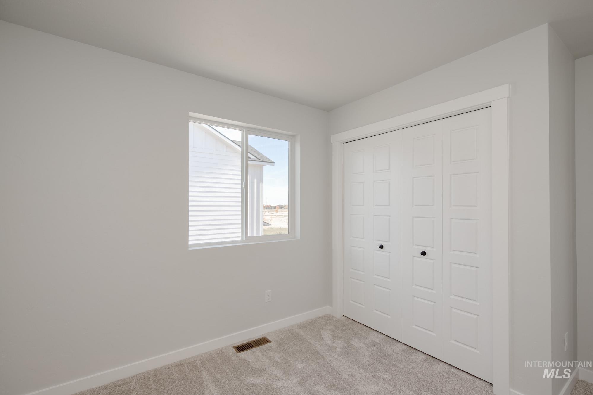 Unfurnished bedroom with light colored carpet and a closet
