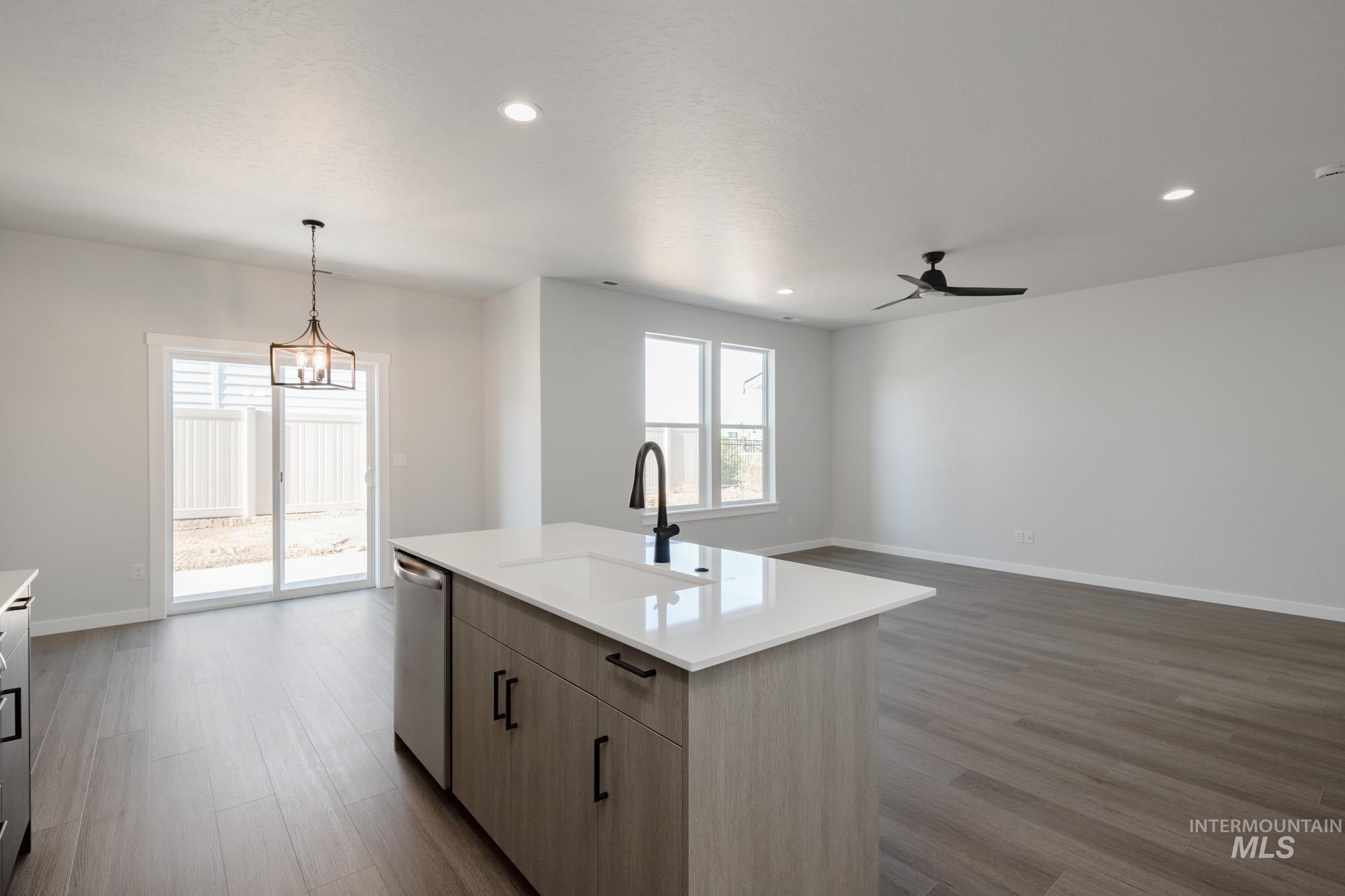 Kitchen with pendant lighting, dark wood-type flooring, recessed lighting, open floor plan, and stainless steel dishwasher