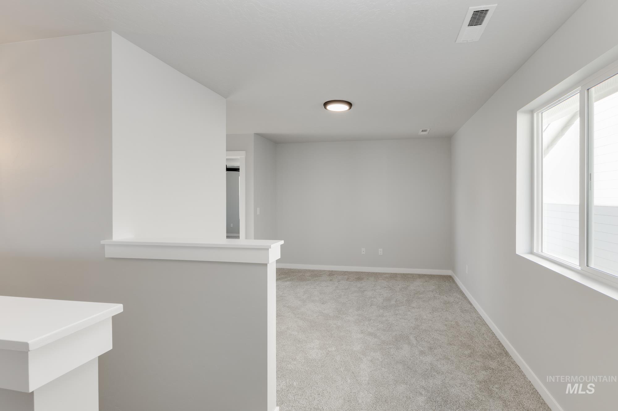 Empty room with light colored carpet and baseboards