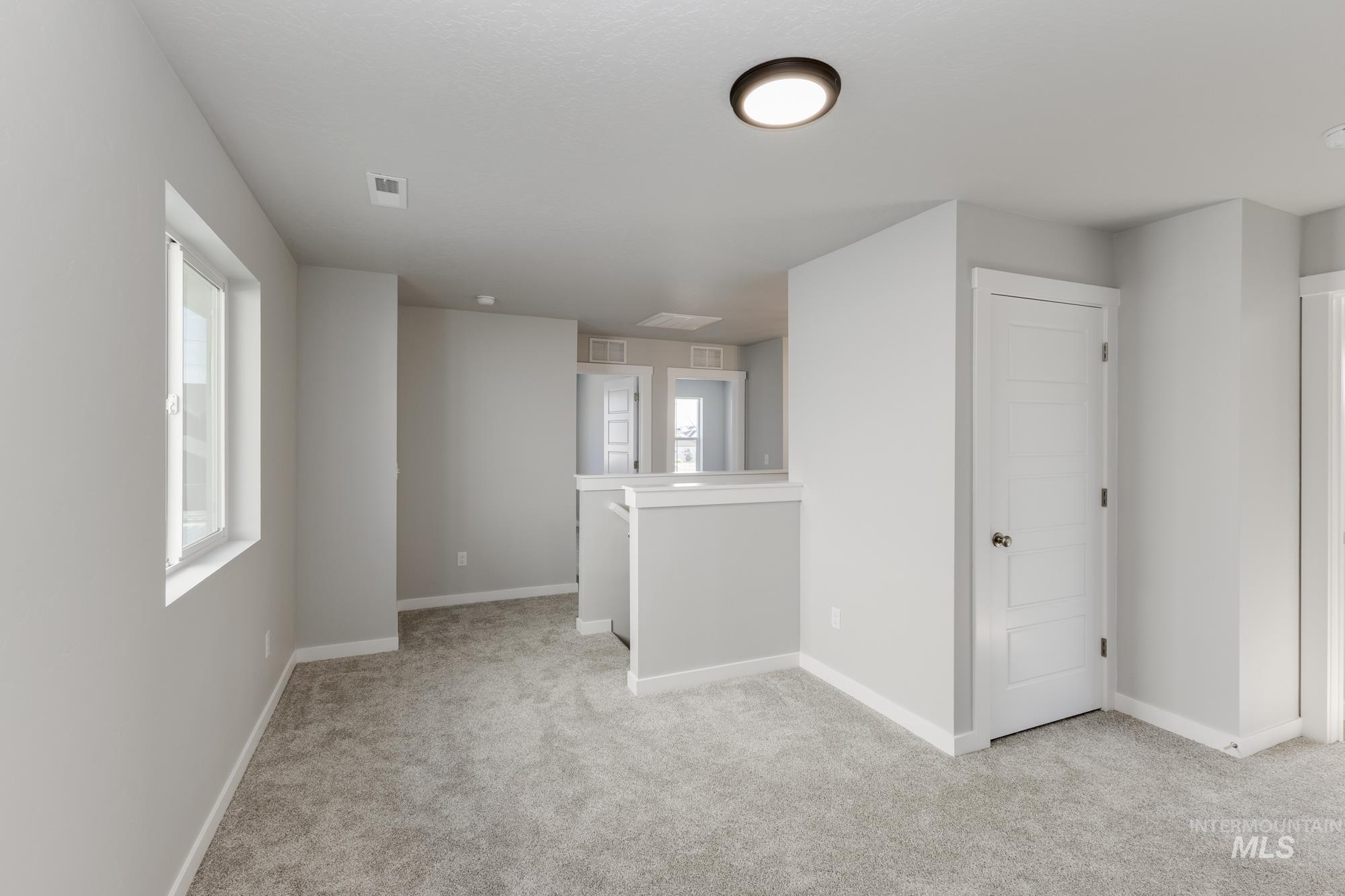 Empty room featuring light carpet and baseboards