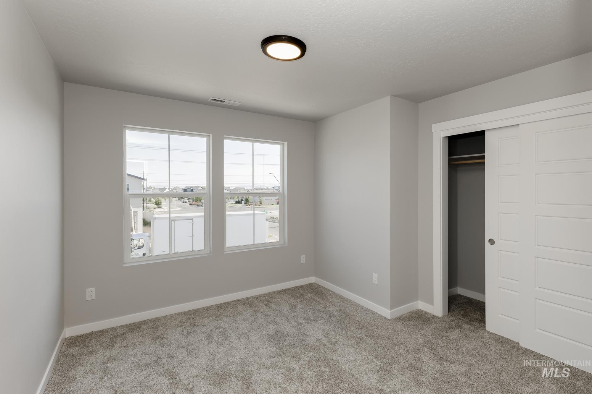 Unfurnished bedroom with light carpet and a closet