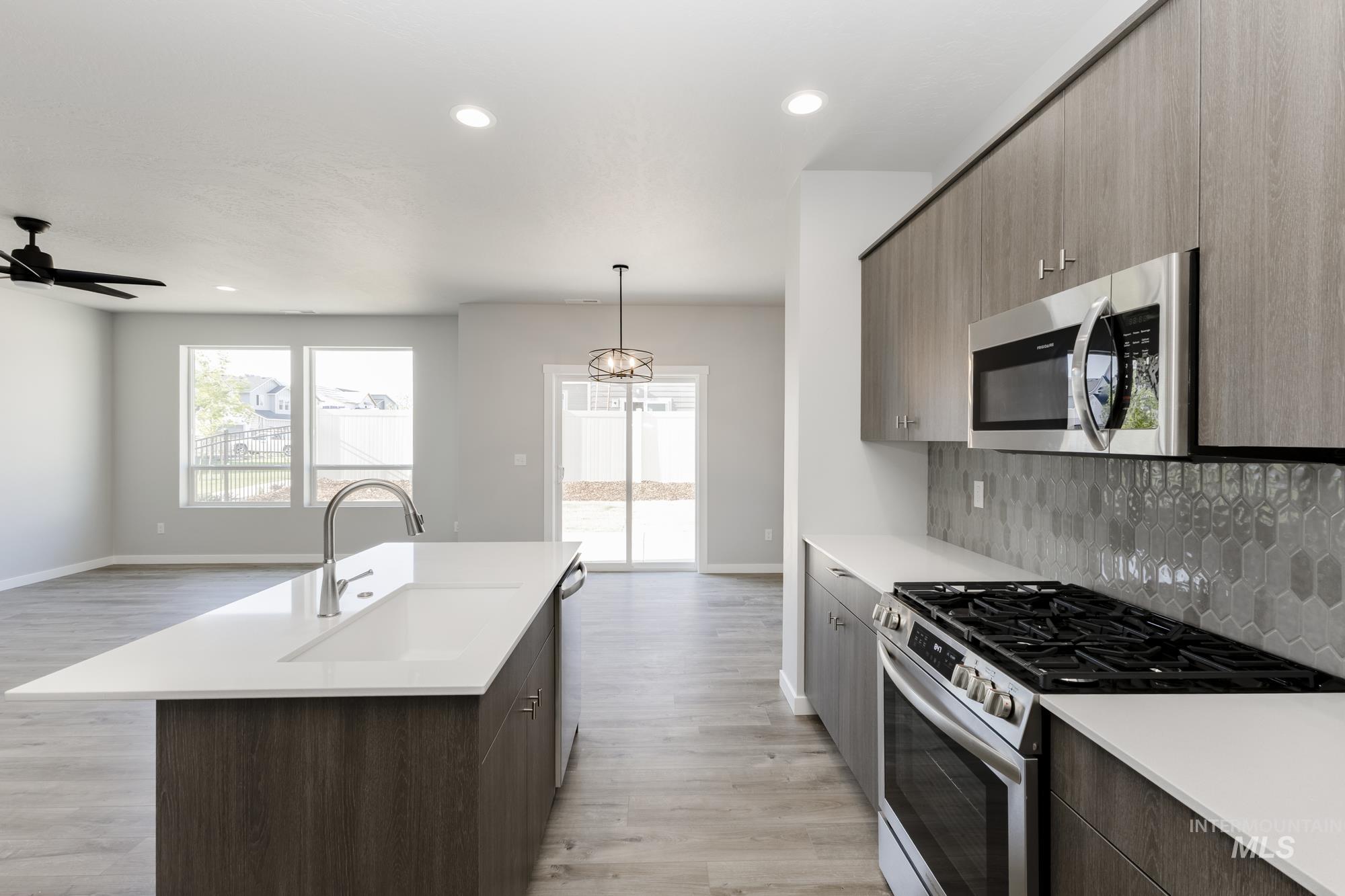 Kitchen with stainless steel appliances, pendant lighting, light wood finished floors, recessed lighting, and decorative backsplash