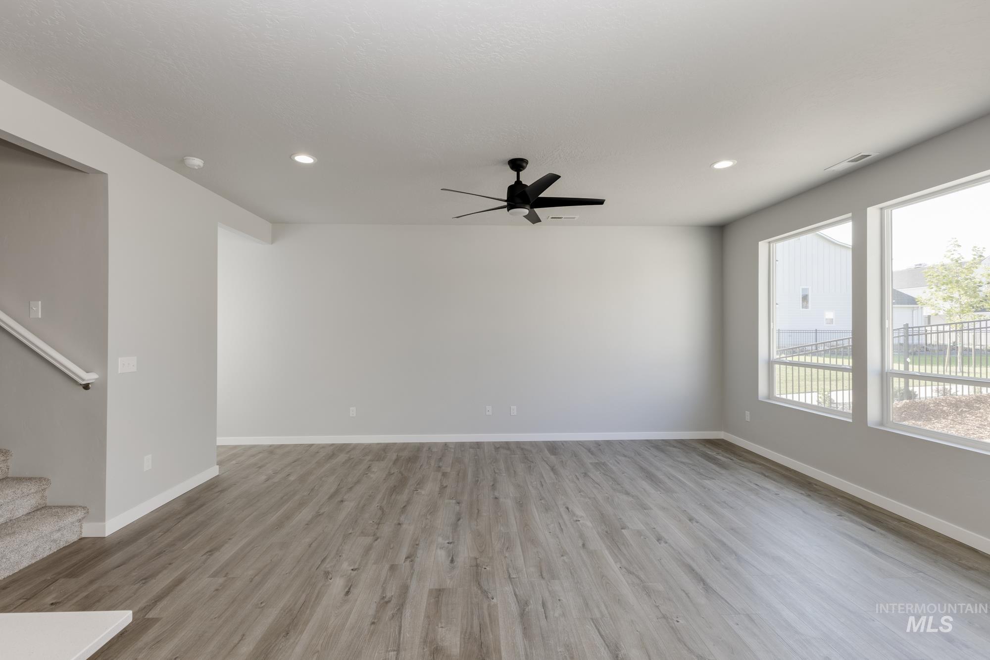 Unfurnished living room featuring light wood-style flooring, stairway, recessed lighting, and ceiling fan