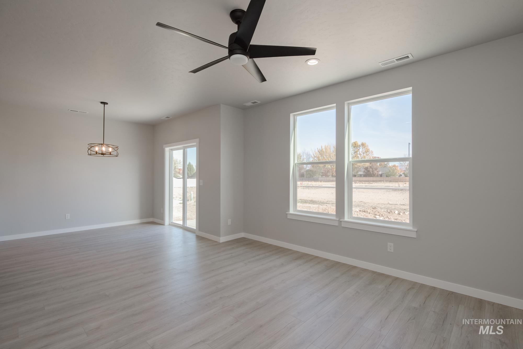 Empty room with healthy amount of natural light, ceiling fan, light wood-style floors, a chandelier, and recessed lighting