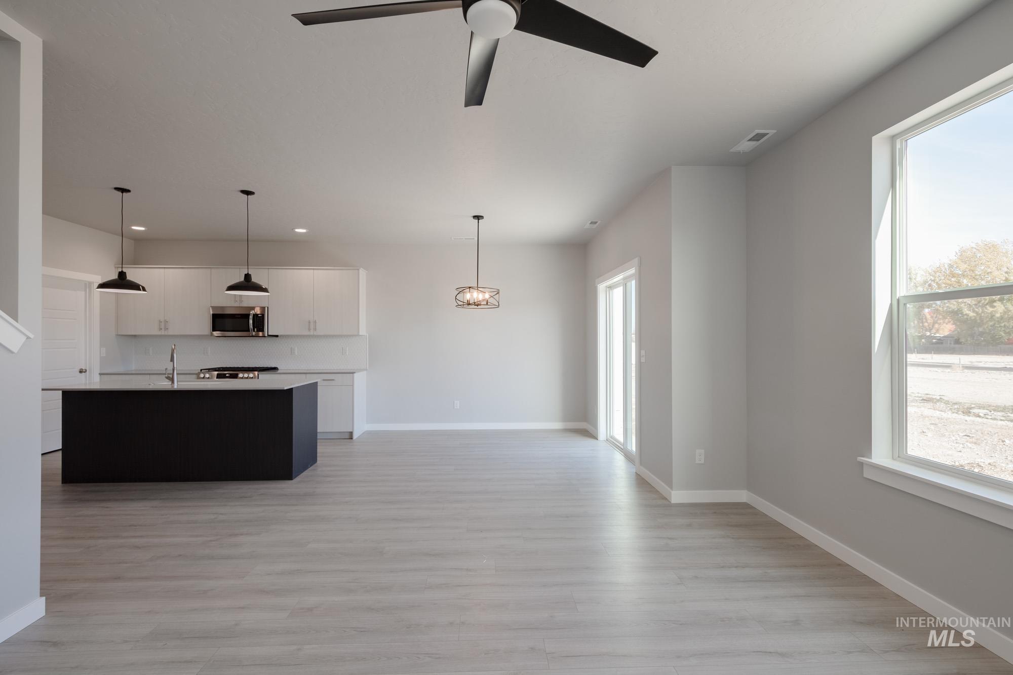 Kitchen with a kitchen island with sink, open floor plan, hanging light fixtures, and light wood-type flooring