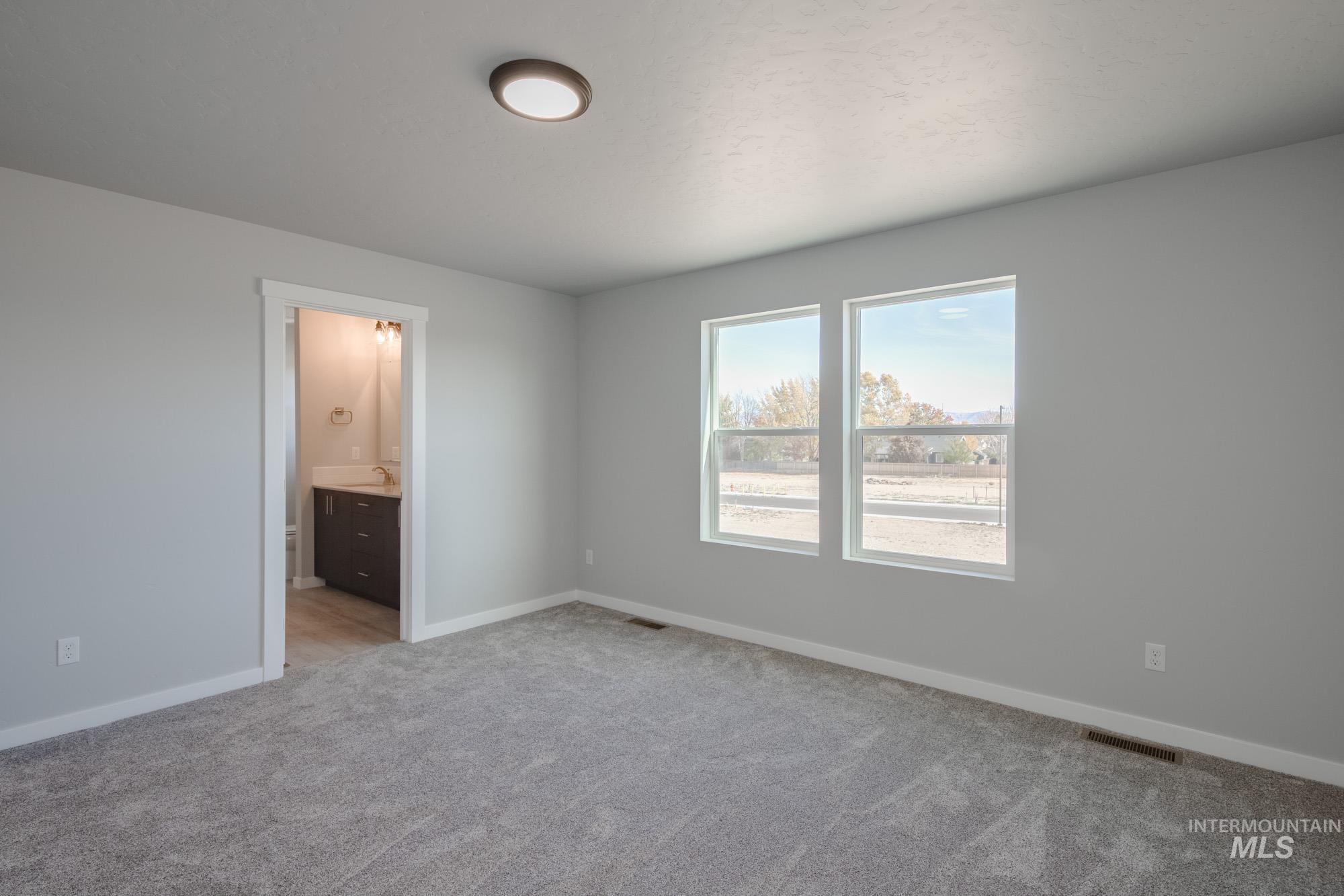 Unfurnished bedroom with light carpet and connected bathroom