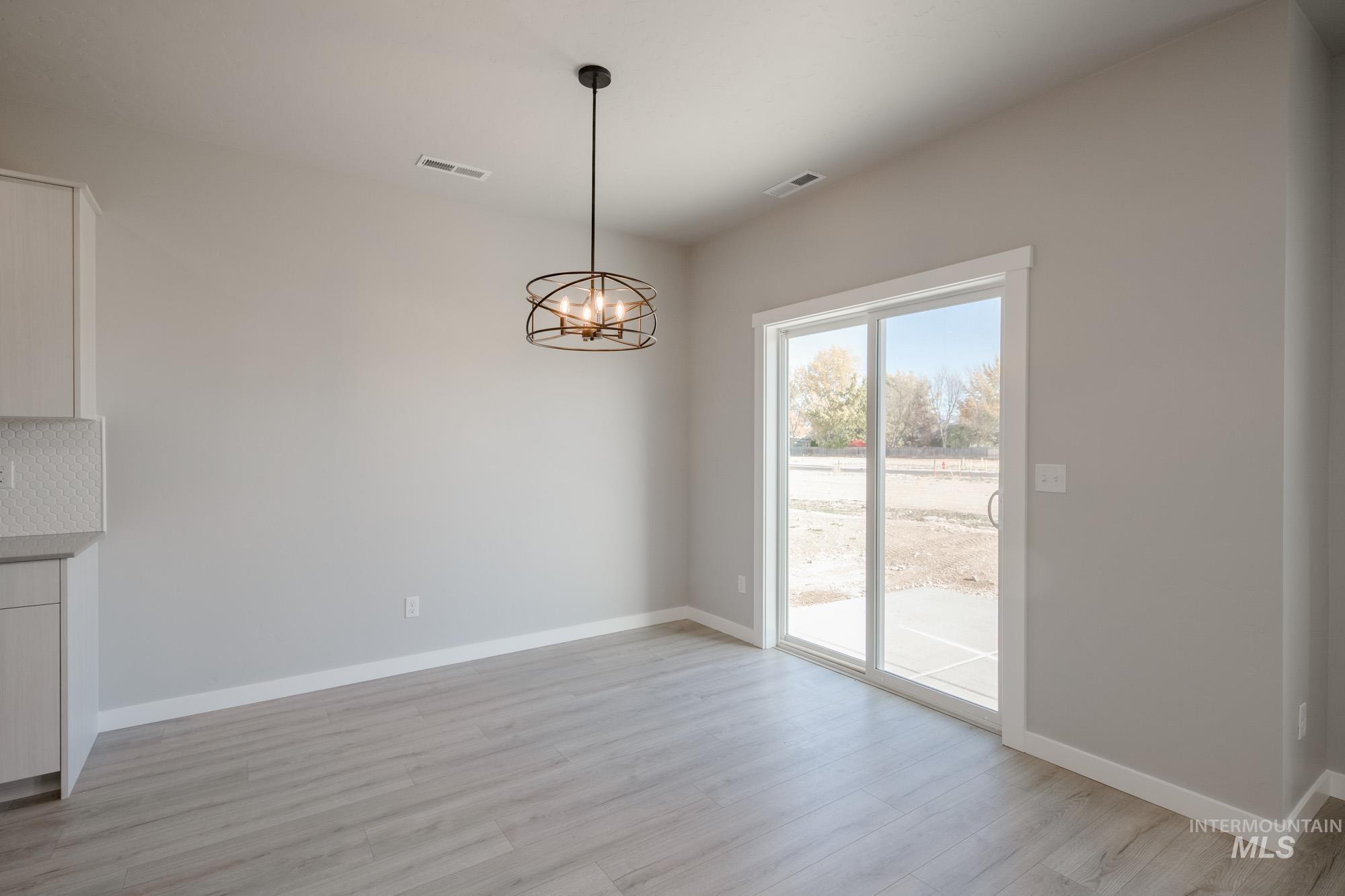 Unfurnished dining area with a chandelier and light wood-style flooring