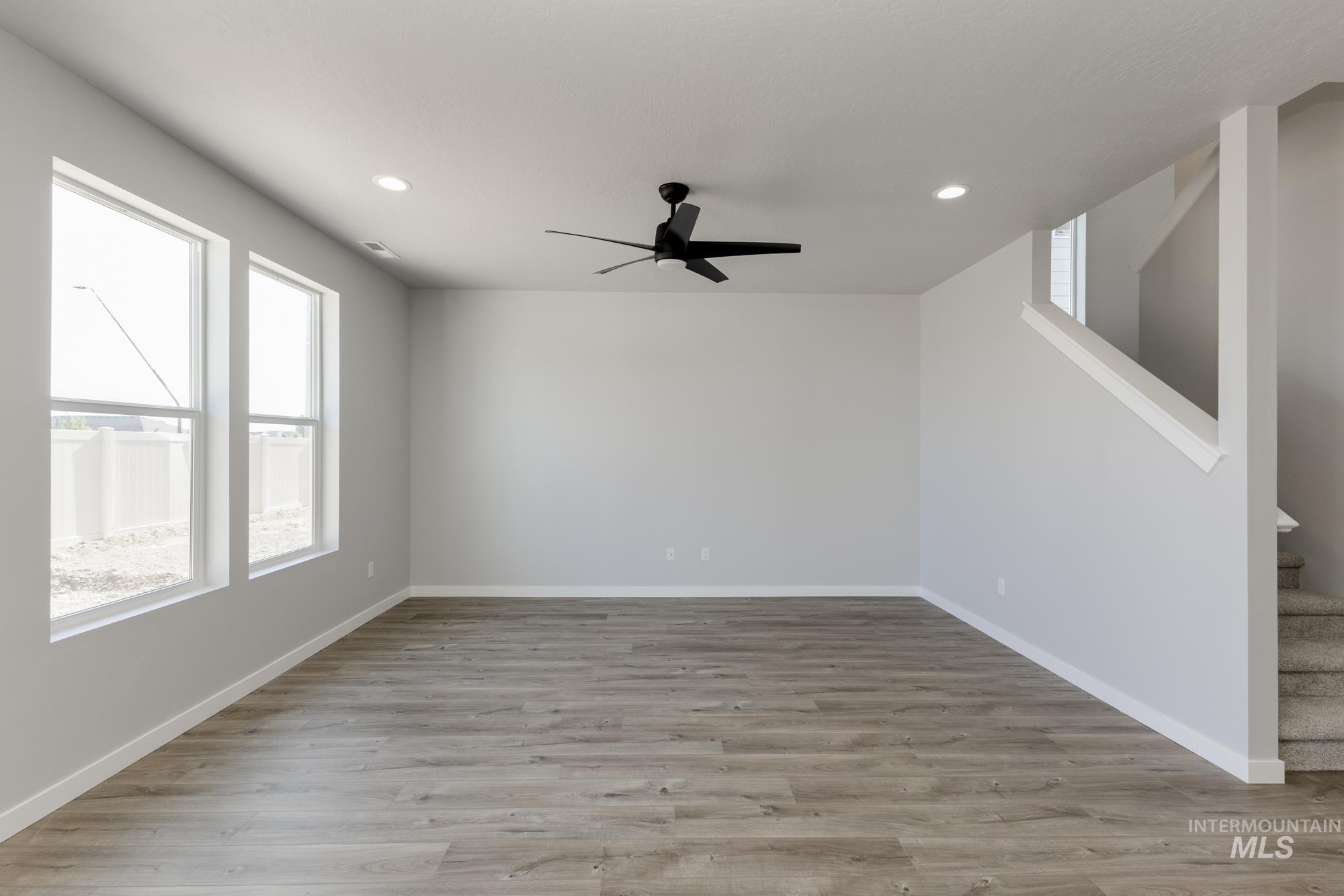 Empty room with light wood-type flooring, recessed lighting, stairs, and ceiling fan