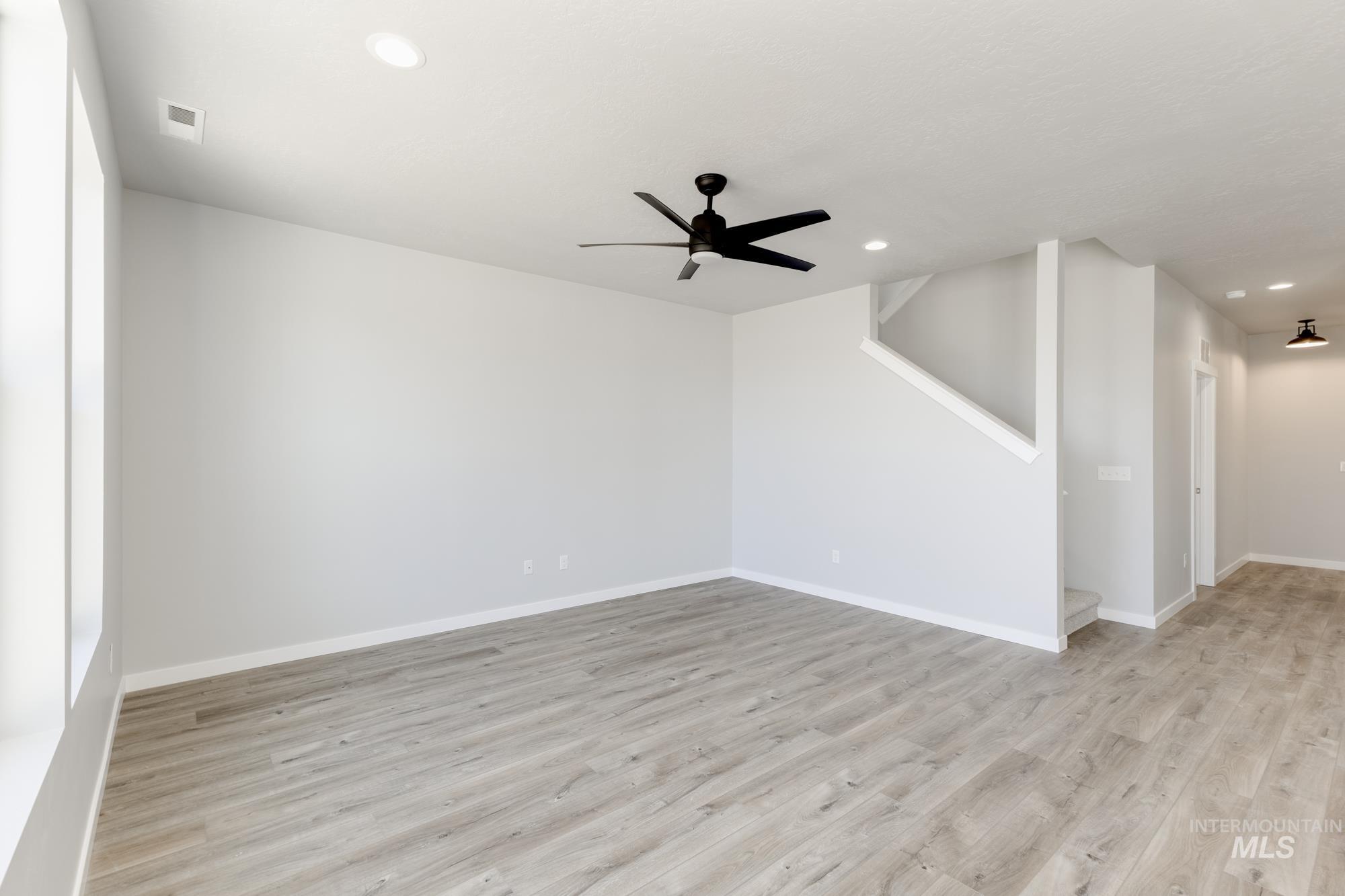 Spare room featuring light wood-type flooring, a ceiling fan, recessed lighting, and stairs