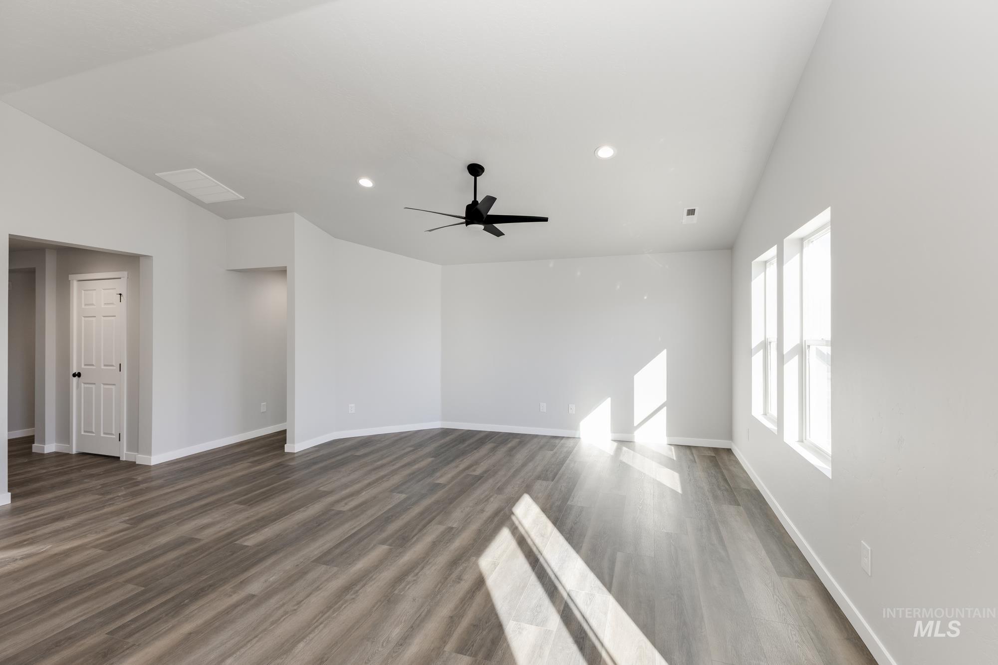 Unfurnished living room with lofted ceiling, recessed lighting, dark wood-style flooring, and a ceiling fan