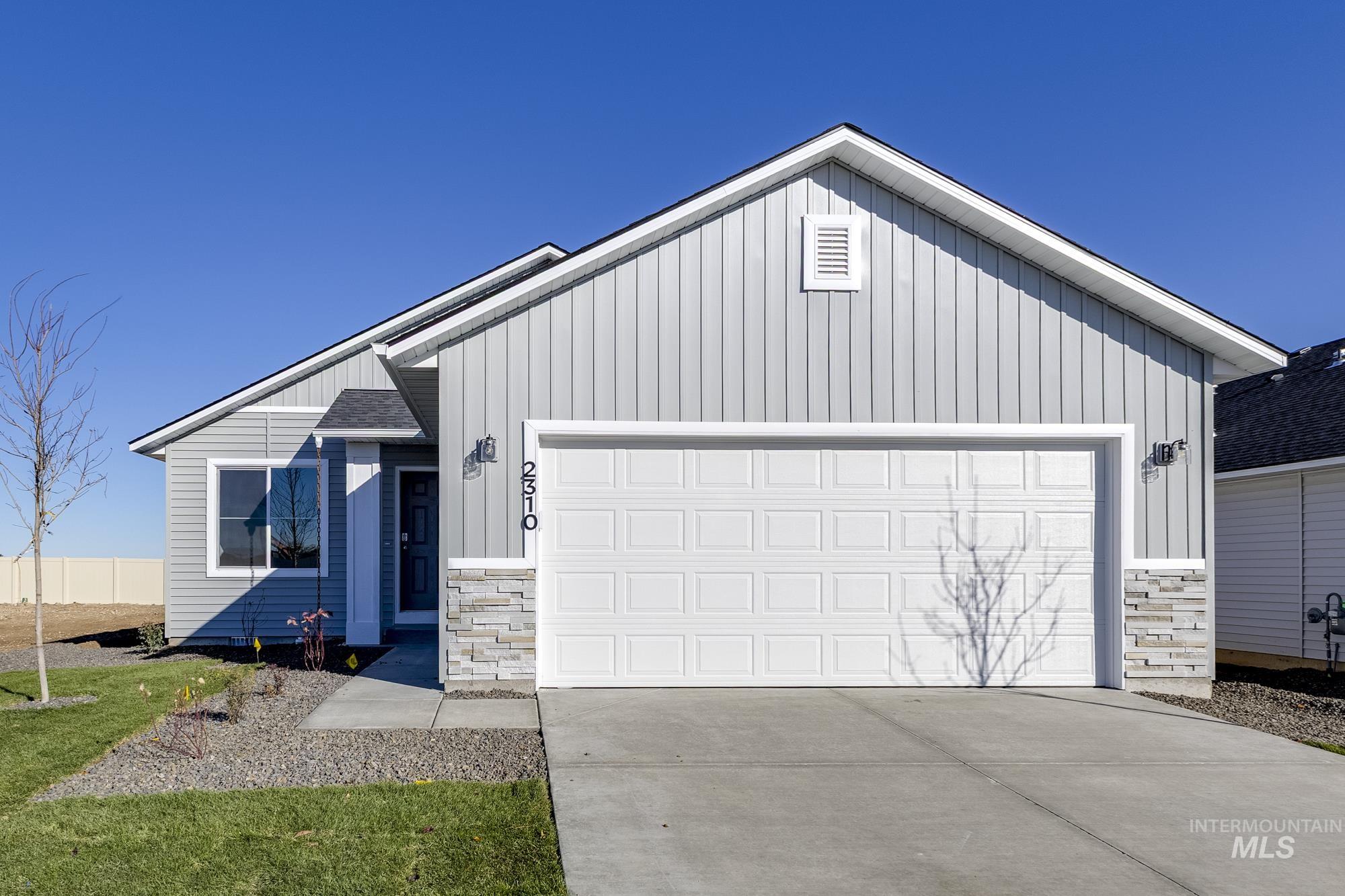 View of front of property featuring stone siding, board and batten siding, driveway, and an attached garage