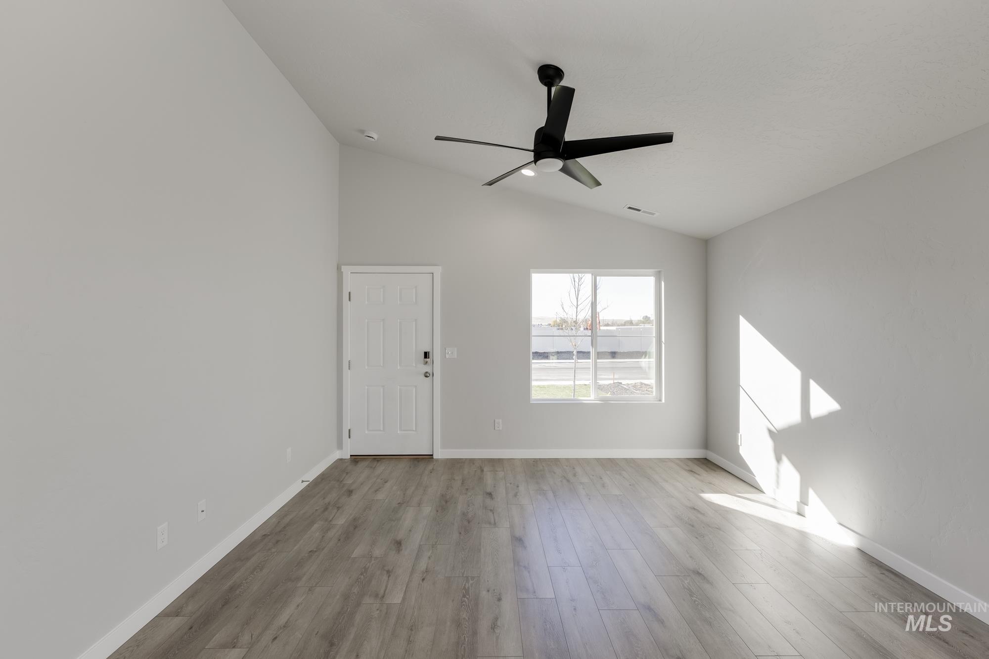 Unfurnished room with lofted ceiling, light wood finished floors, and a ceiling fan