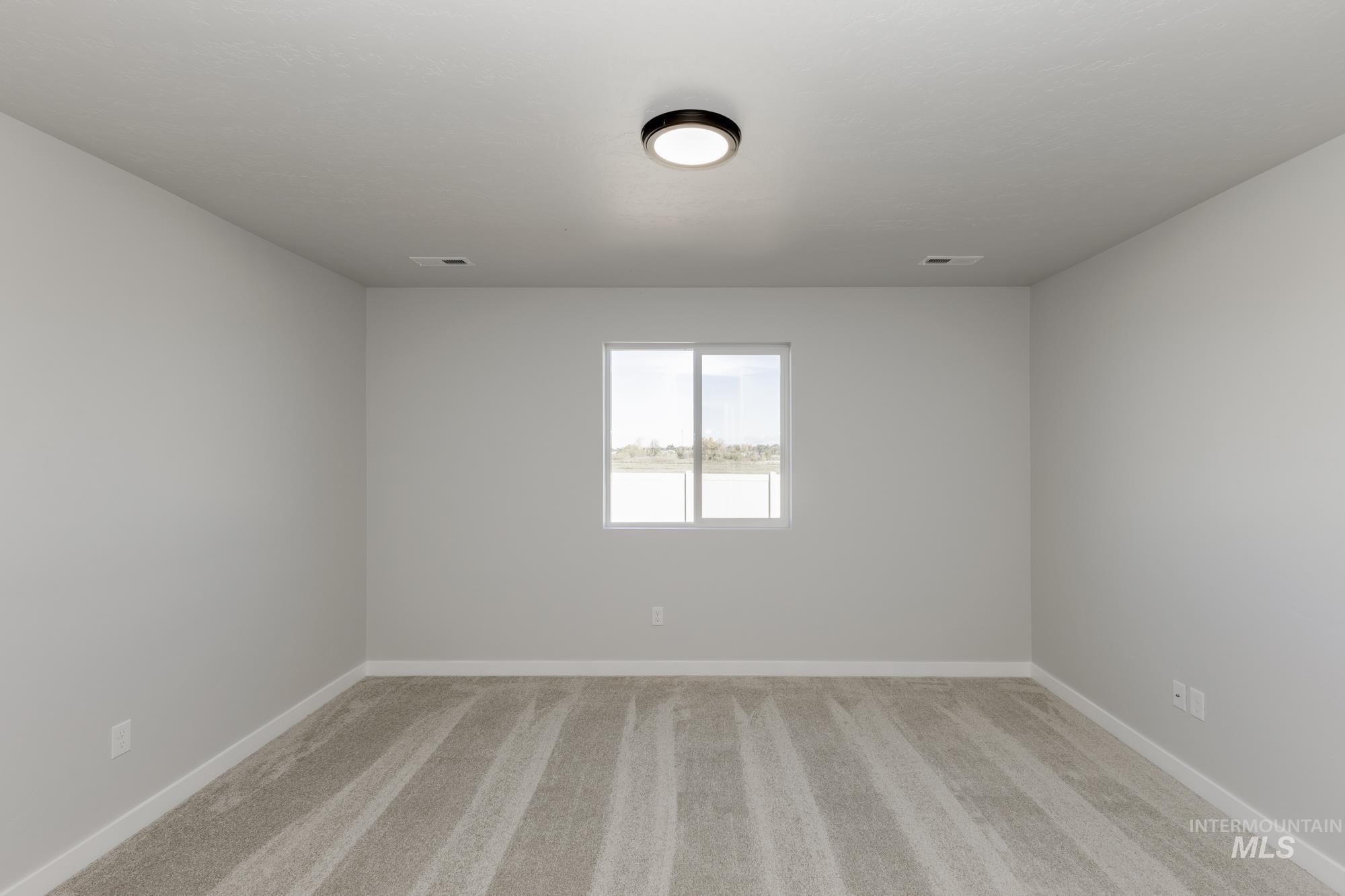 Spare room with light carpet and baseboards