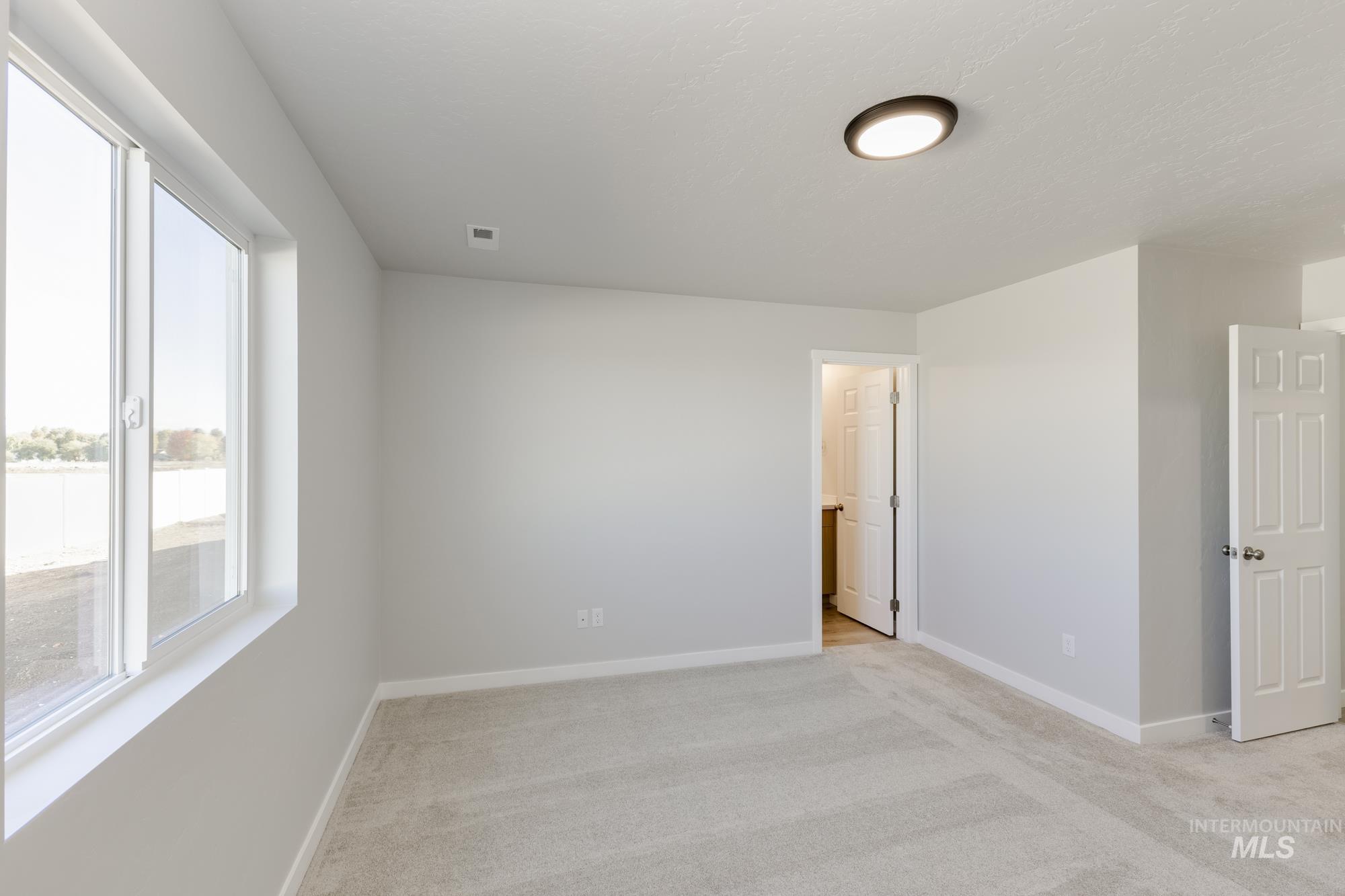Unfurnished bedroom featuring light colored carpet and baseboards