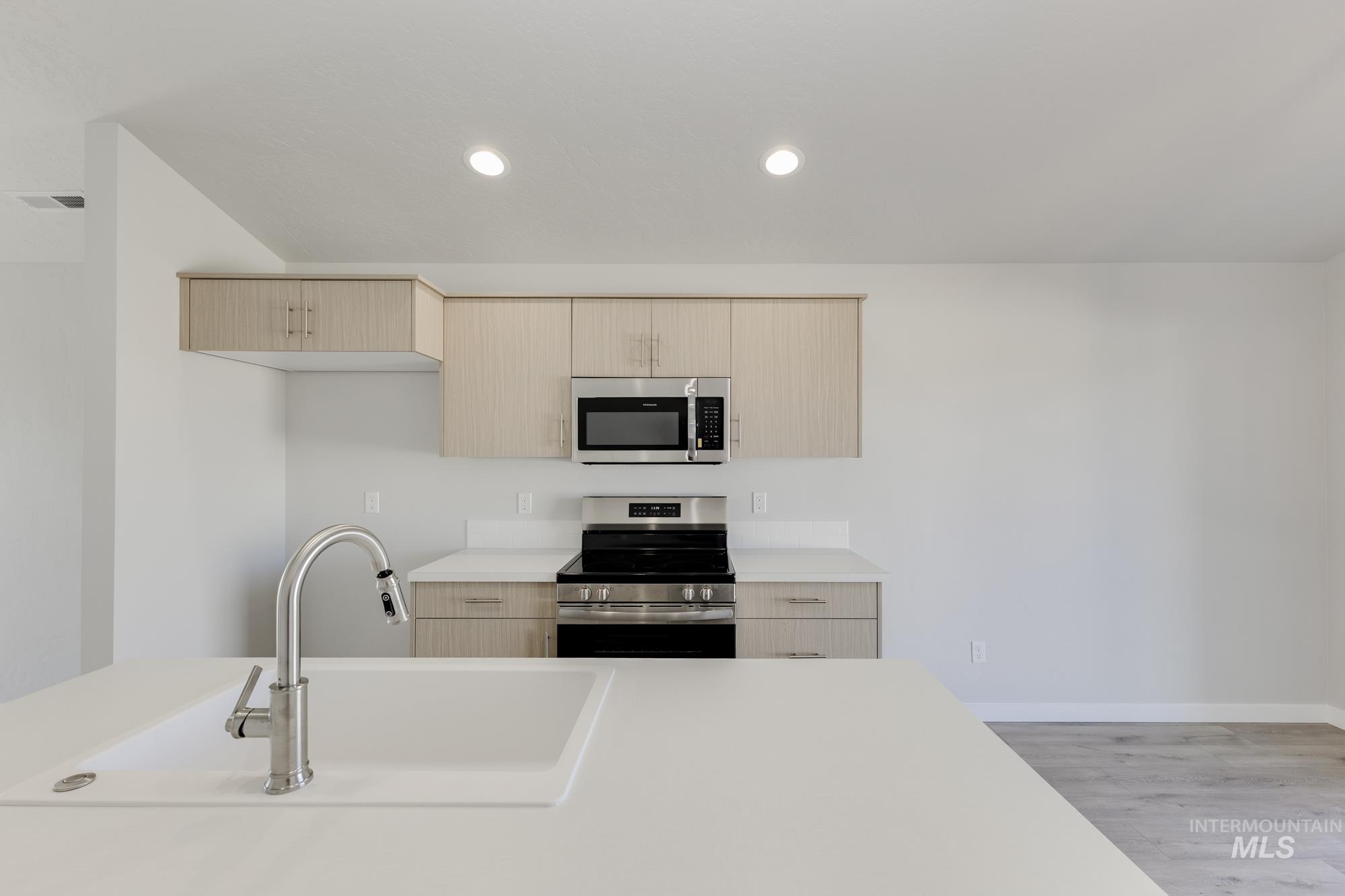 Kitchen featuring stainless steel appliances, light brown cabinets, light wood-style floors, recessed lighting, and modern cabinets