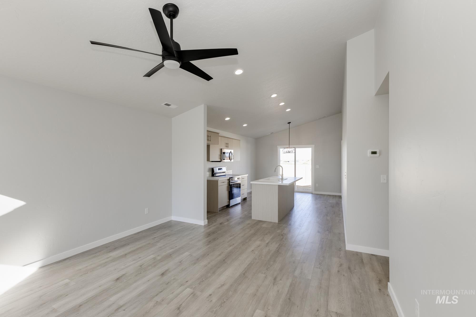 Unfurnished living room featuring light wood-style flooring, lofted ceiling, a ceiling fan, and recessed lighting