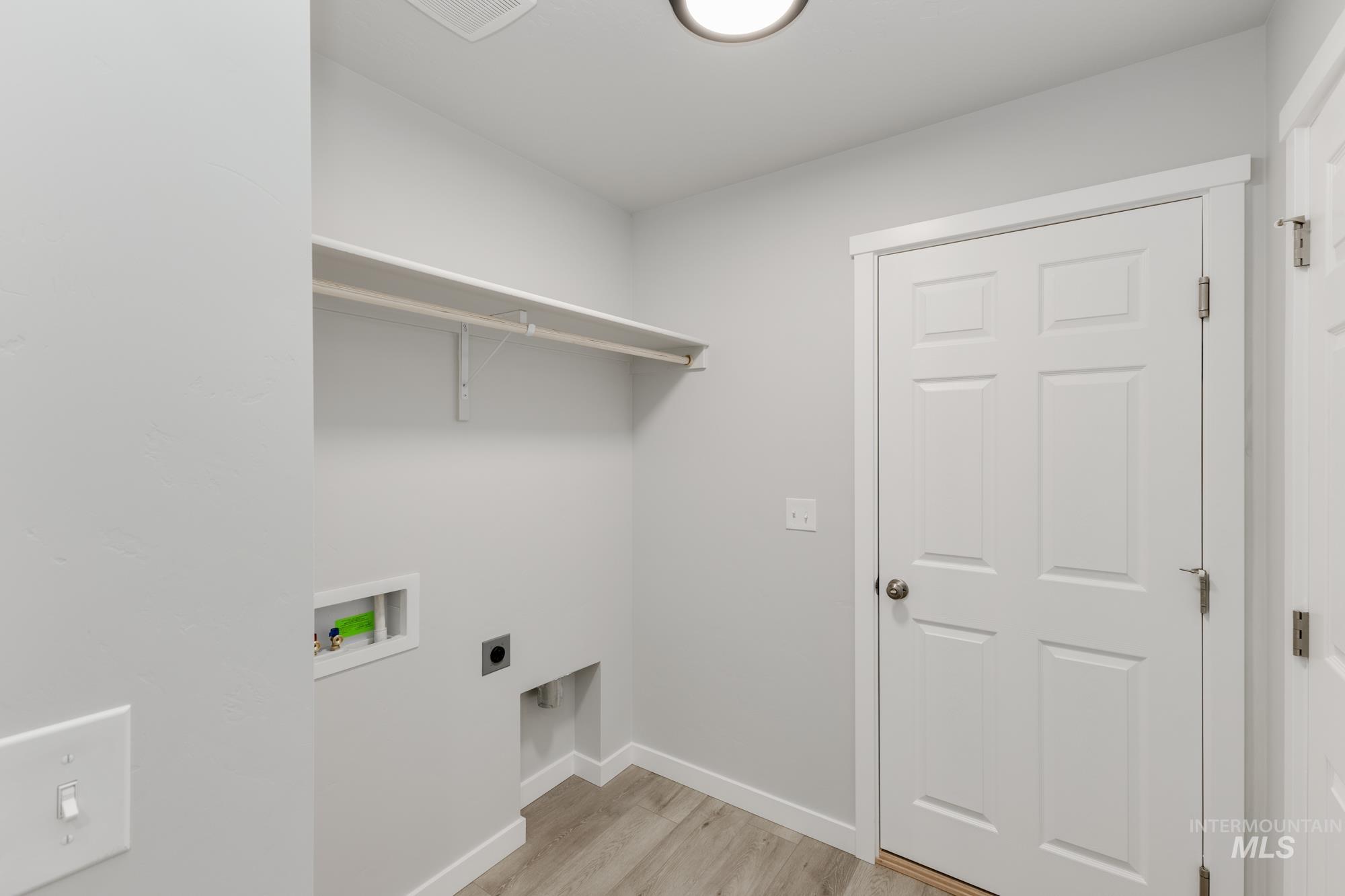 Laundry room featuring light wood finished floors, hookup for a washing machine, and hookup for an electric dryer