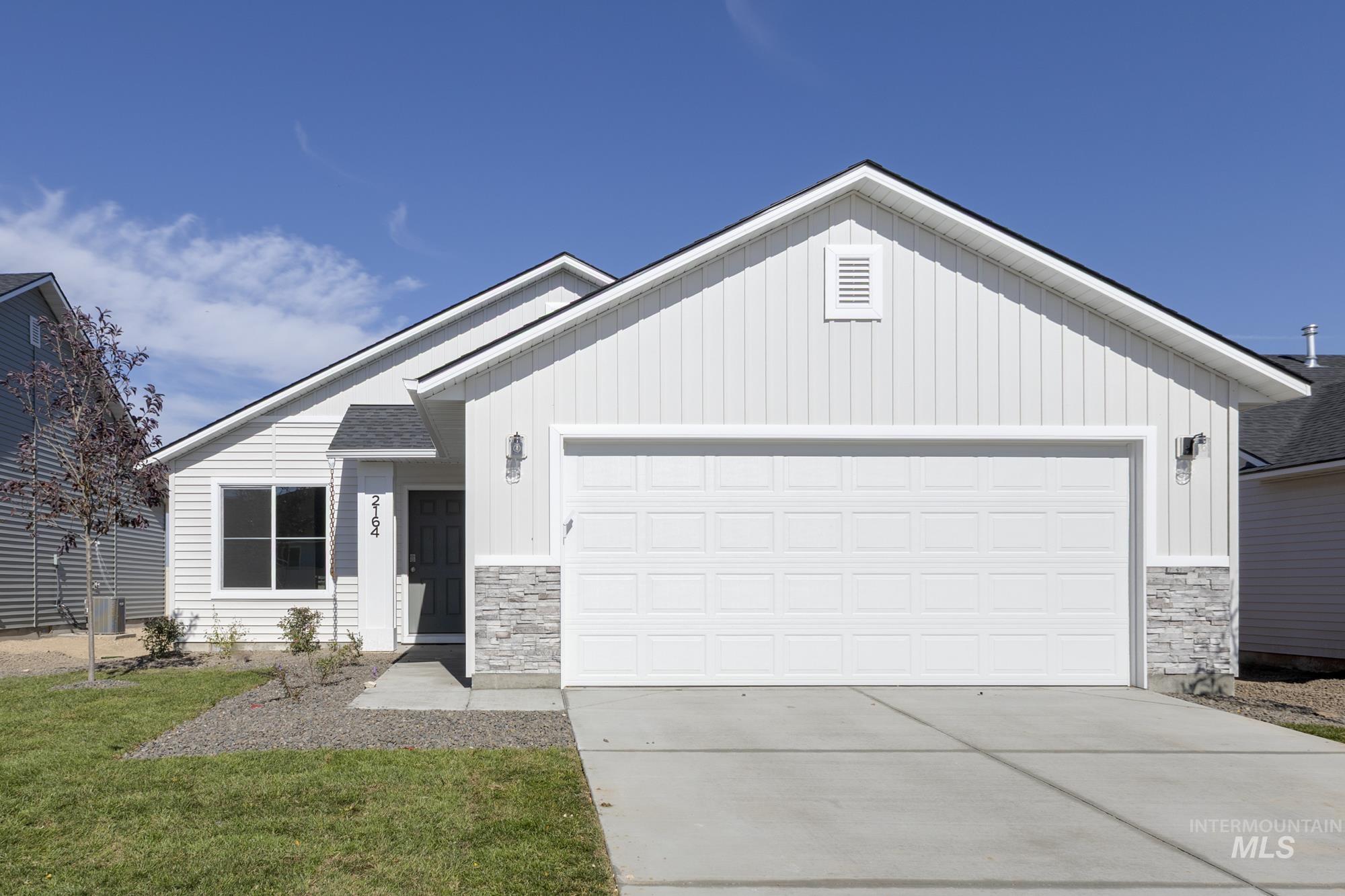 Ranch-style home featuring stone siding, board and batten siding, driveway, and an attached garage