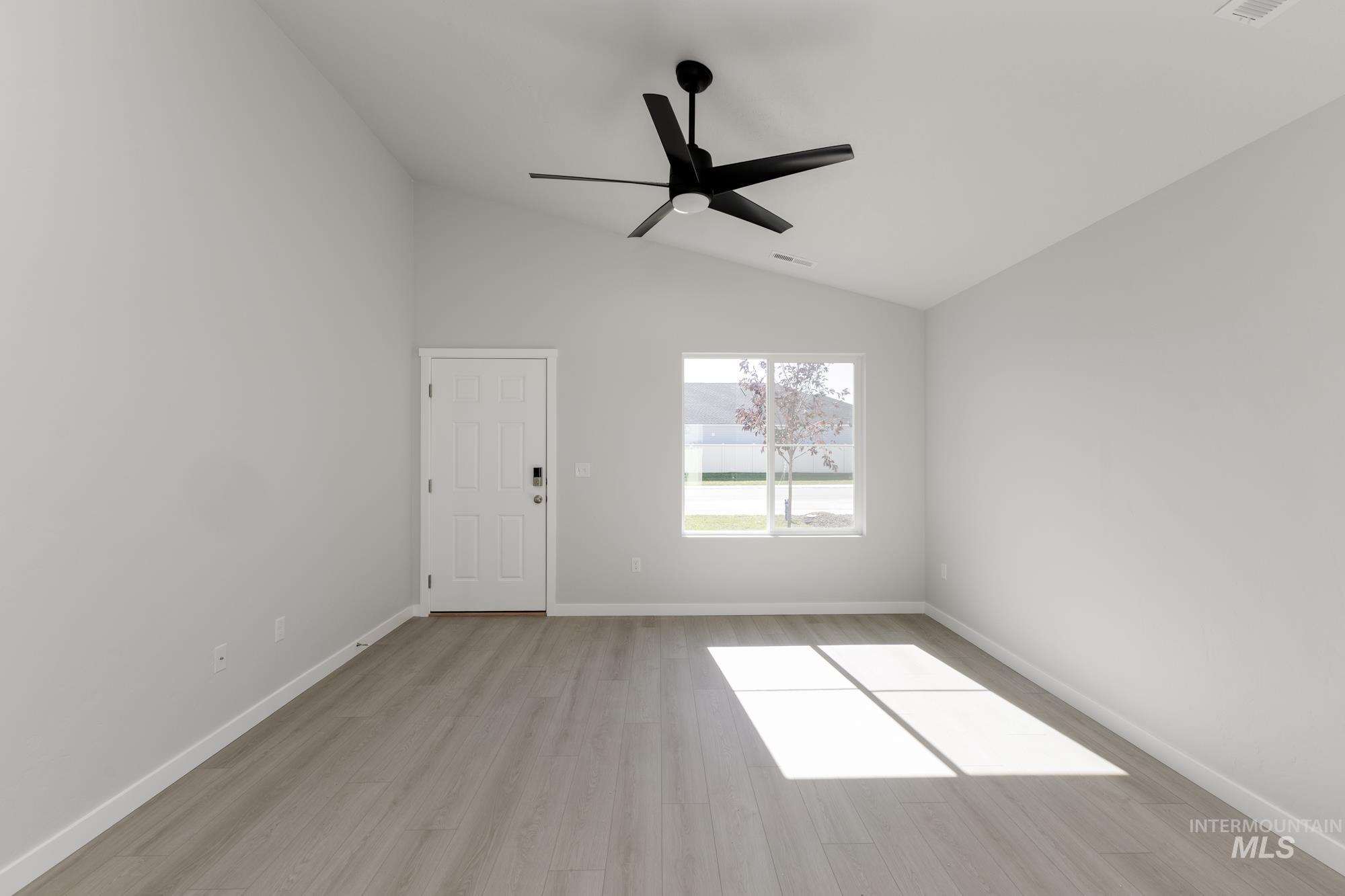Unfurnished room with vaulted ceiling, light wood-style floors, and ceiling fan