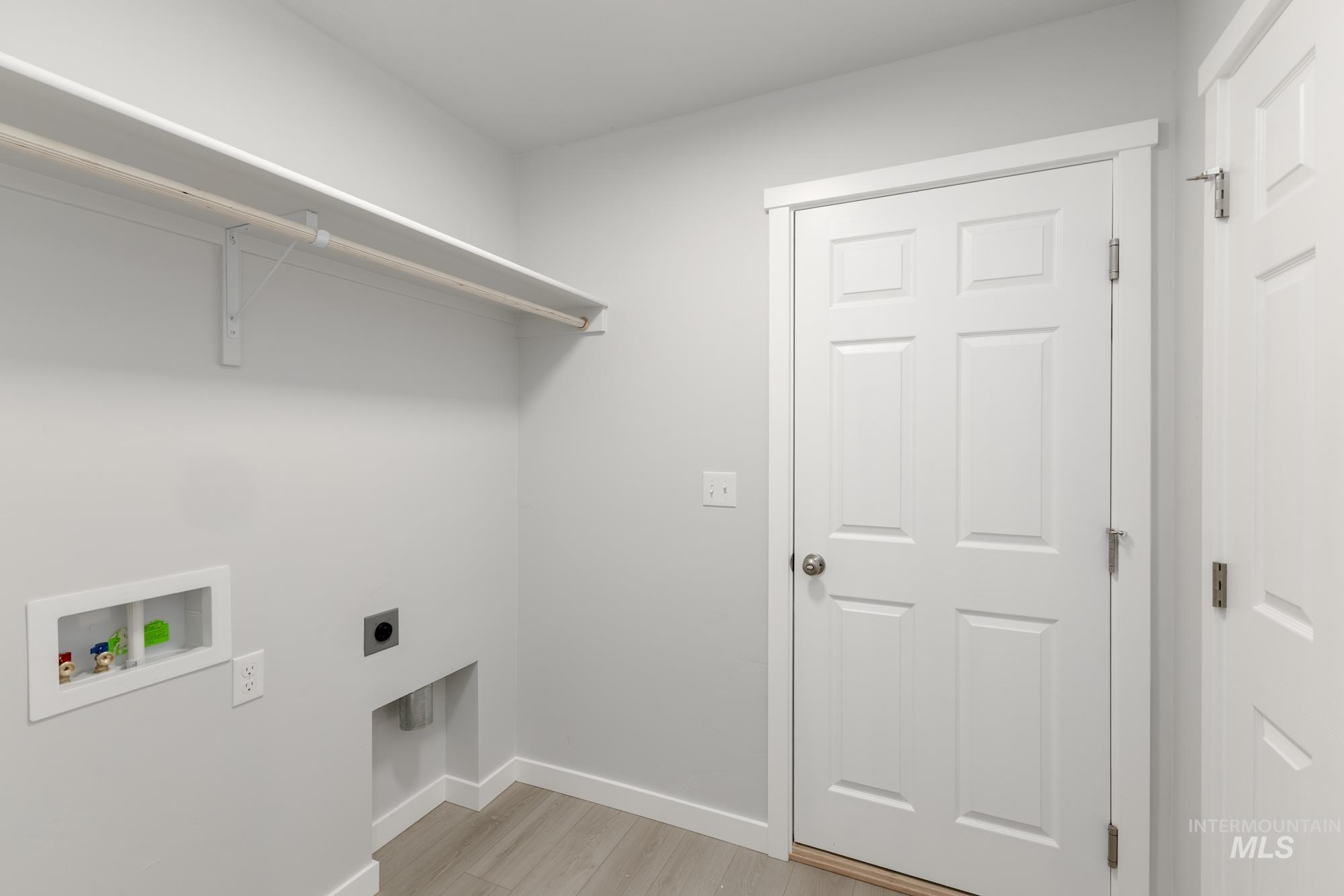 Laundry room with light wood-type flooring, hookup for an electric dryer, and hookup for a washing machine