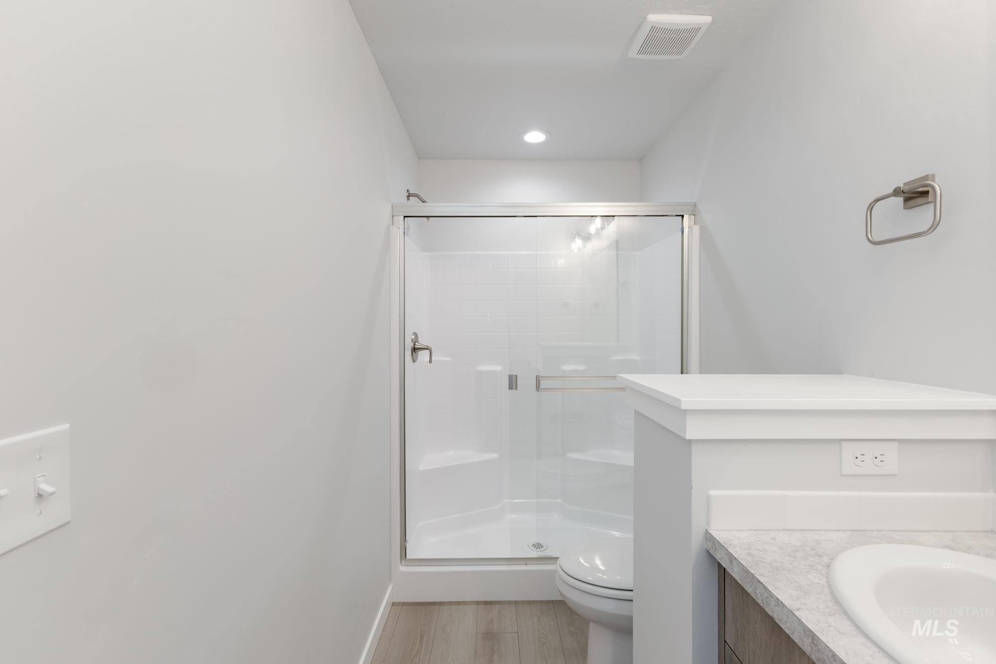 Full bathroom featuring vanity, a shower stall, light wood-style floors, and recessed lighting