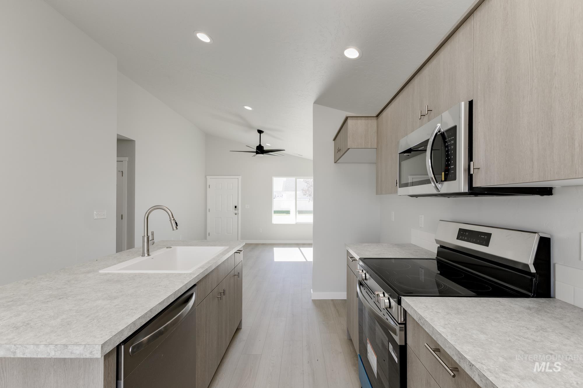 Kitchen featuring stainless steel appliances, lofted ceiling, modern cabinets, light countertops, and recessed lighting