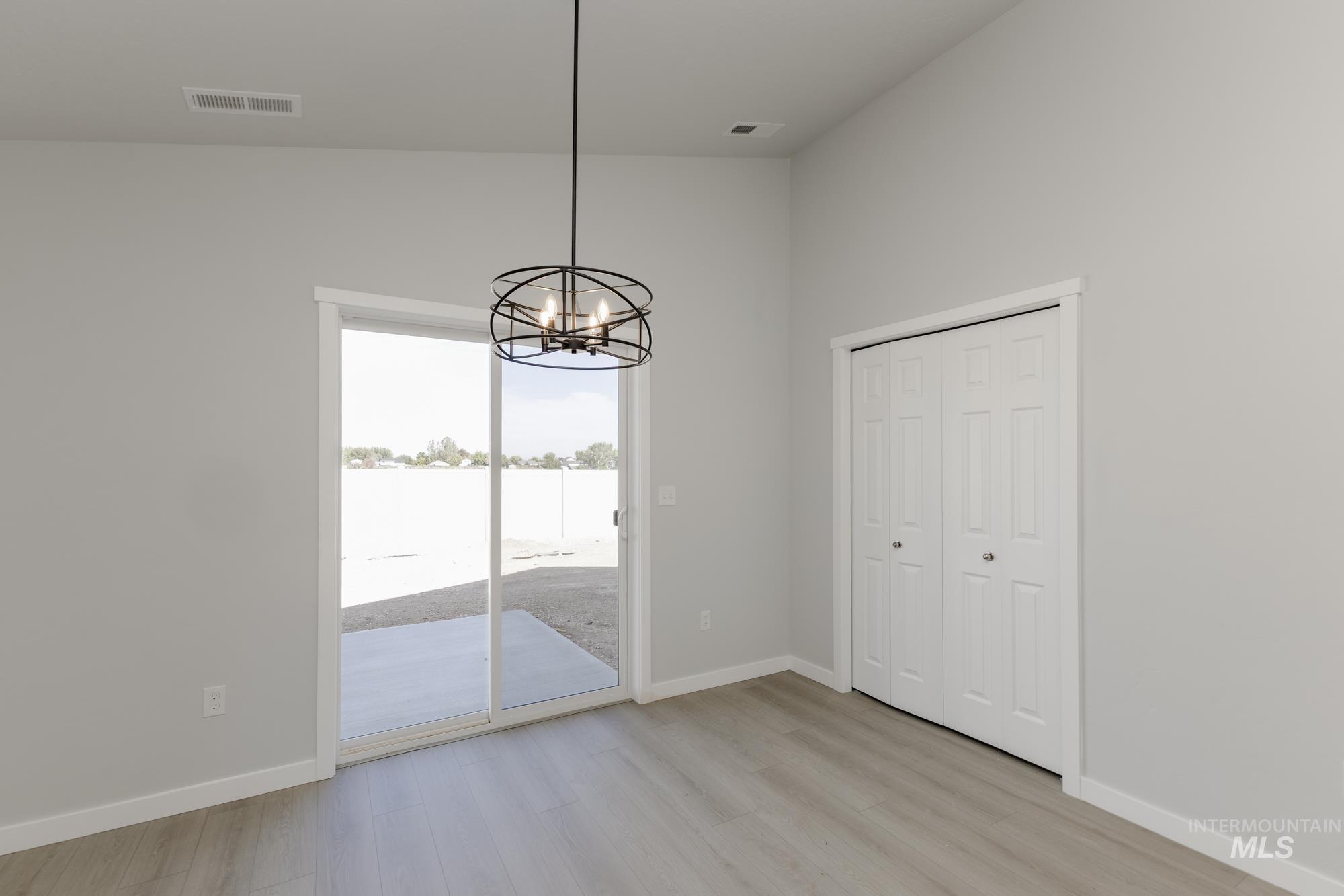 Unfurnished dining area featuring light wood finished floors, a chandelier, and a water view