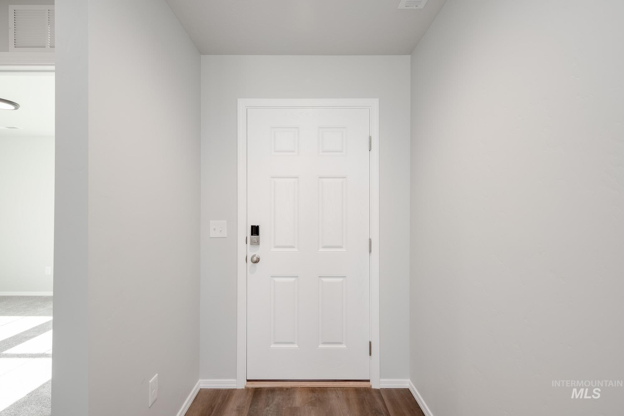Doorway with baseboards and wood finished floors