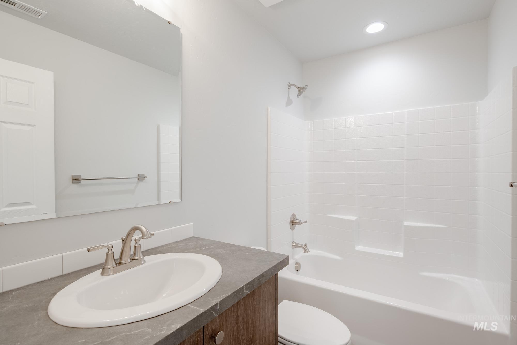 Bathroom with bathtub / shower combination, vanity, and recessed lighting