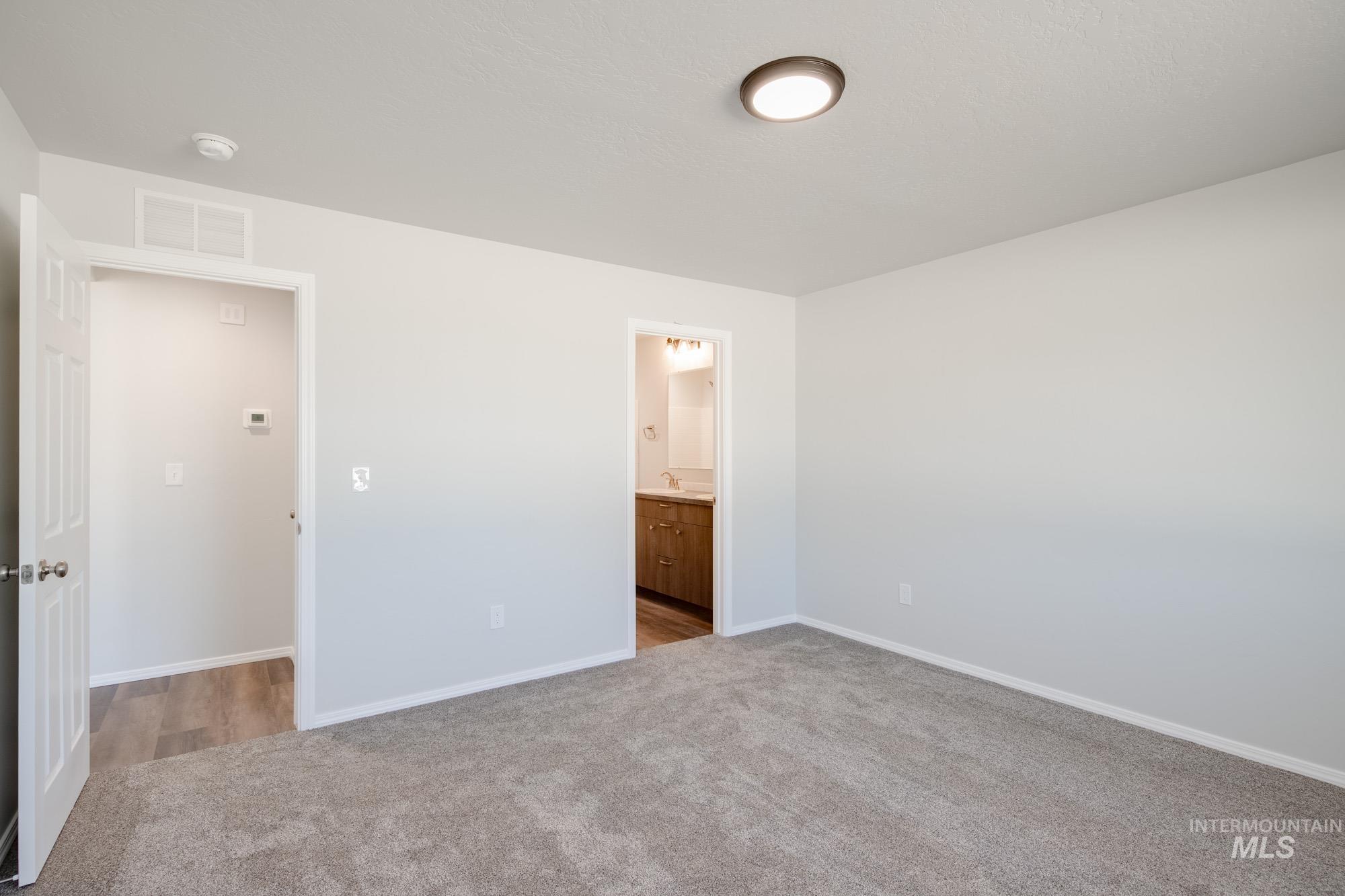 Unfurnished bedroom with light carpet and connected bathroom