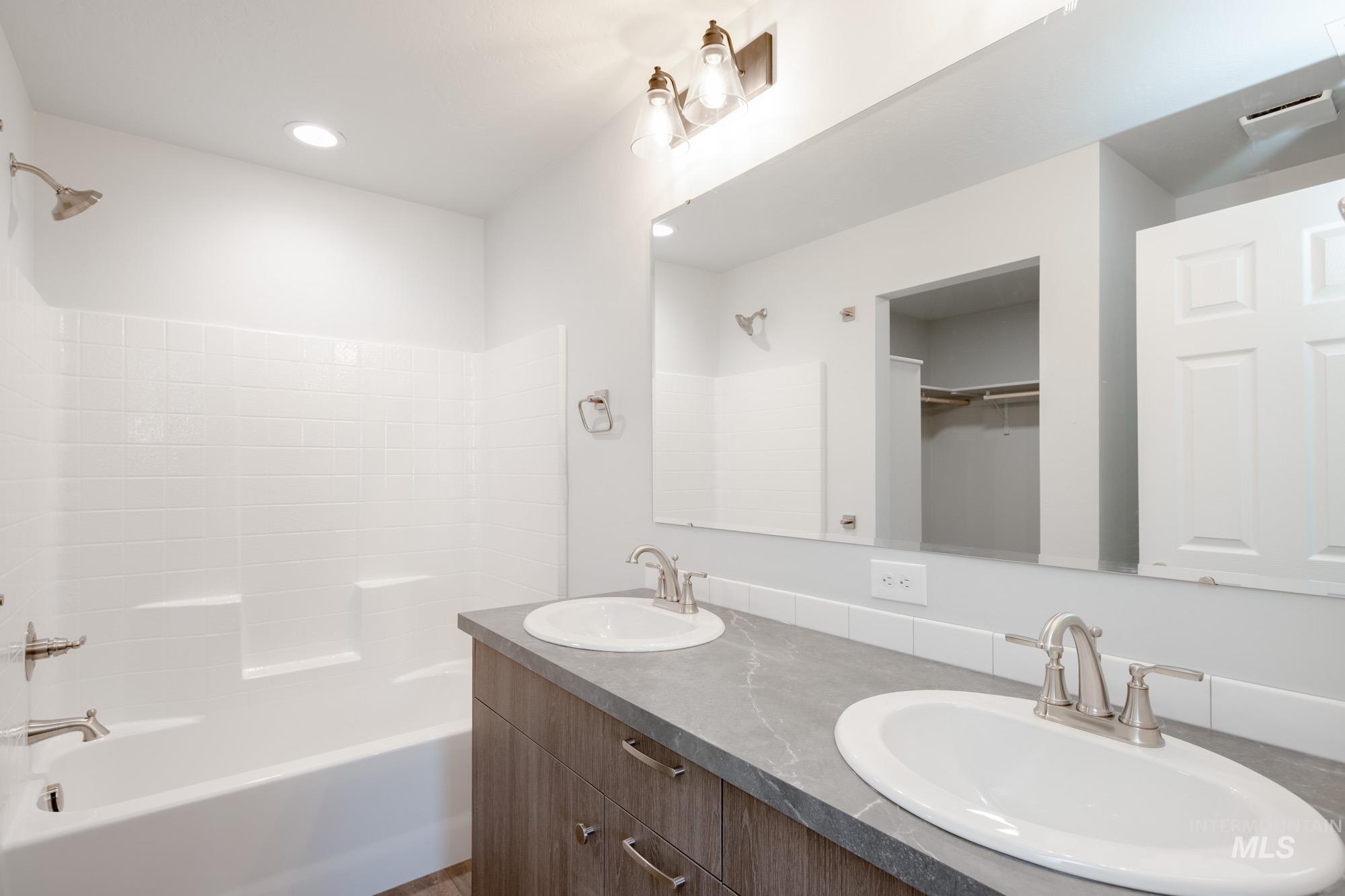 Full bath with tub / shower combination, double vanity, recessed lighting, and a walk in closet