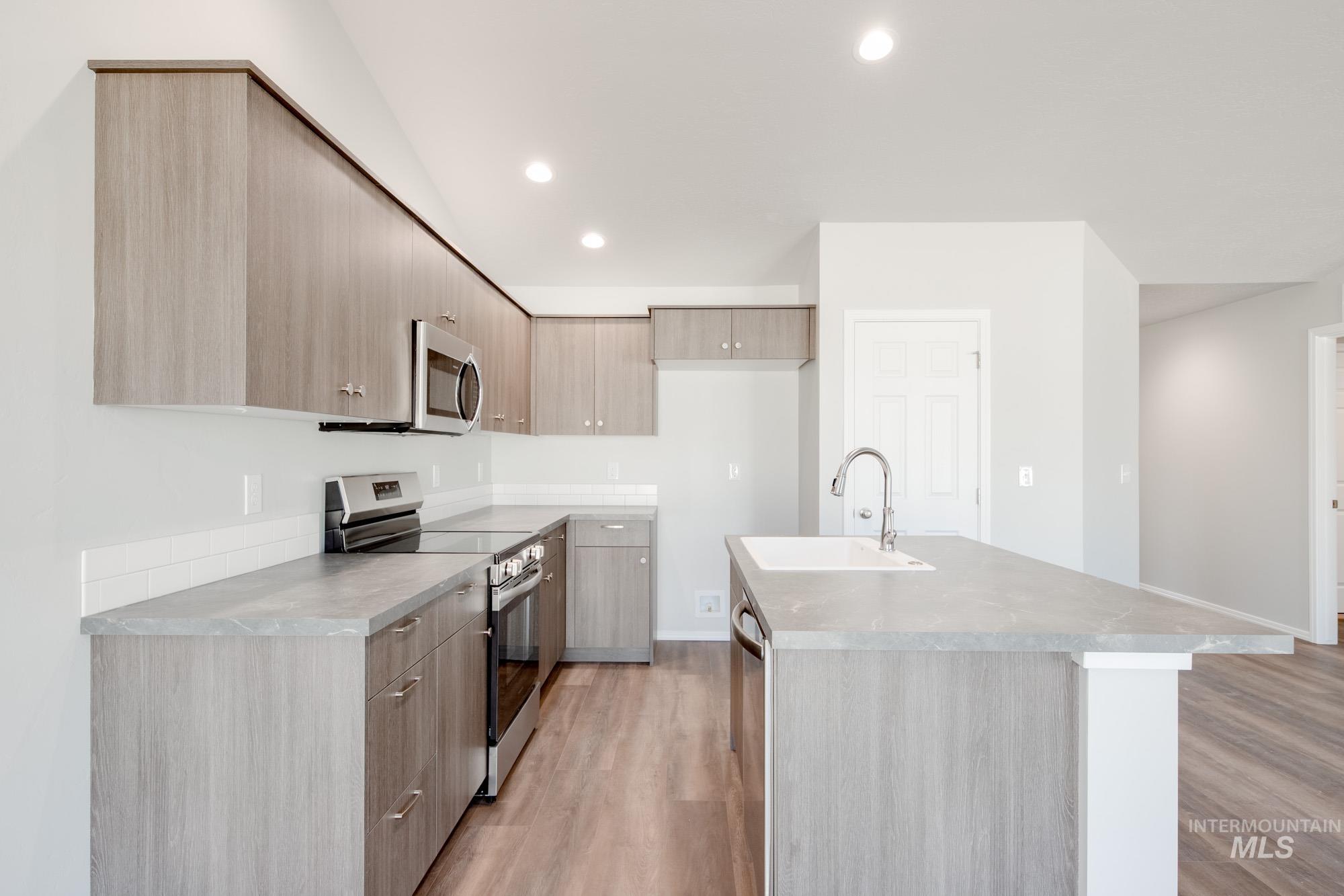 Kitchen with stainless steel appliances, modern cabinets, light brown cabinetry, recessed lighting, and light wood finished floors