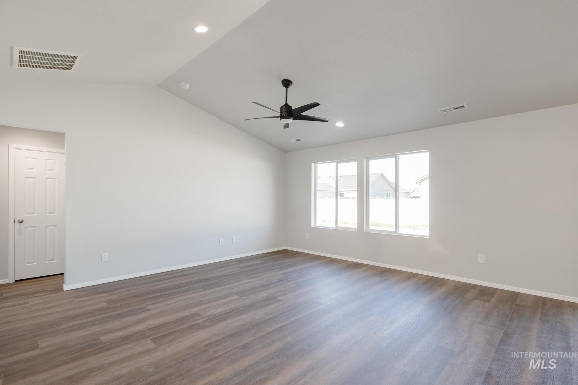 Spare room featuring vaulted ceiling, dark wood finished floors, recessed lighting, and a ceiling fan