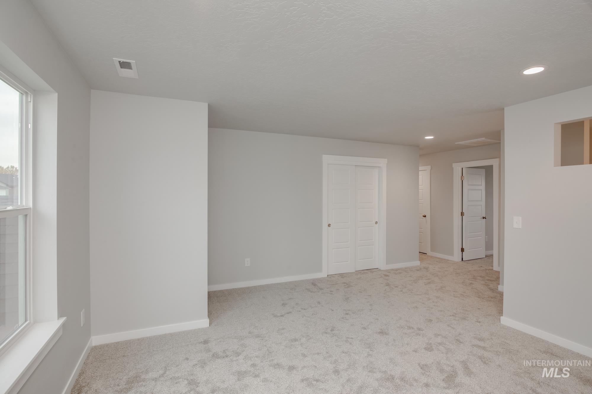 Spare room featuring light colored carpet, recessed lighting, and a textured ceiling
