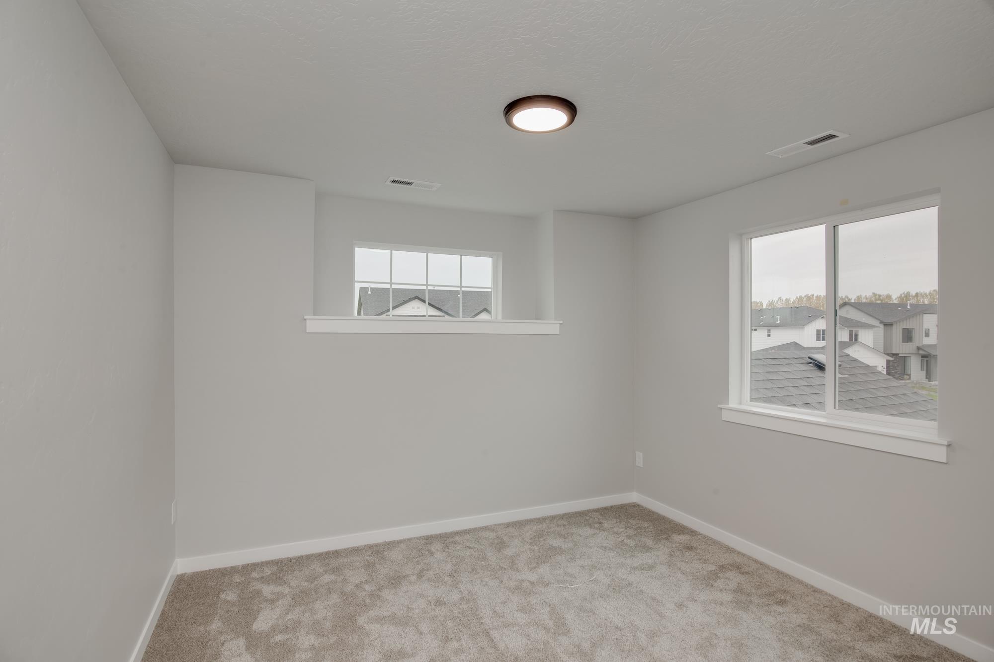 Spare room with baseboards and light colored carpet