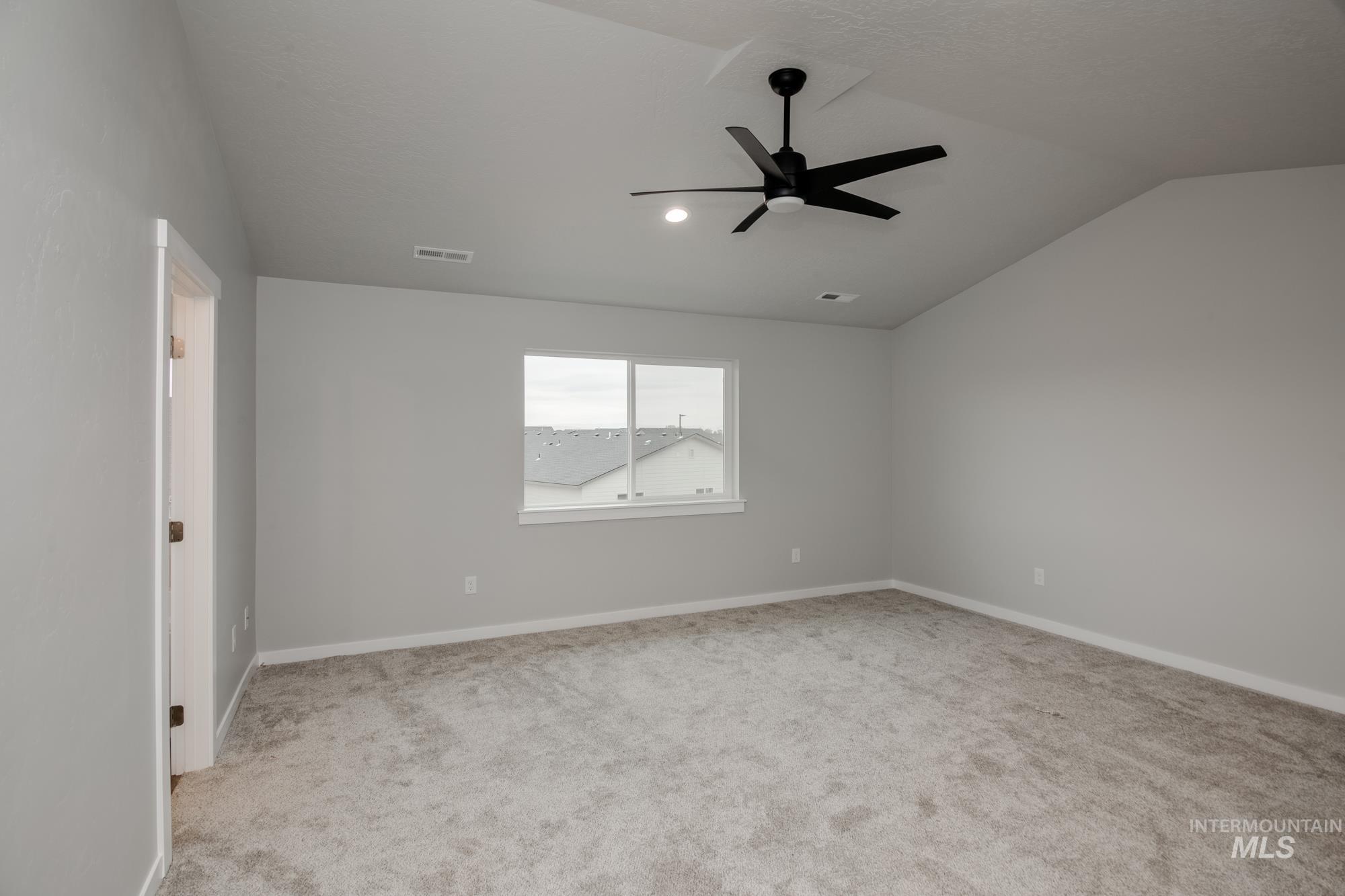 Unfurnished room featuring vaulted ceiling, light carpet, and ceiling fan