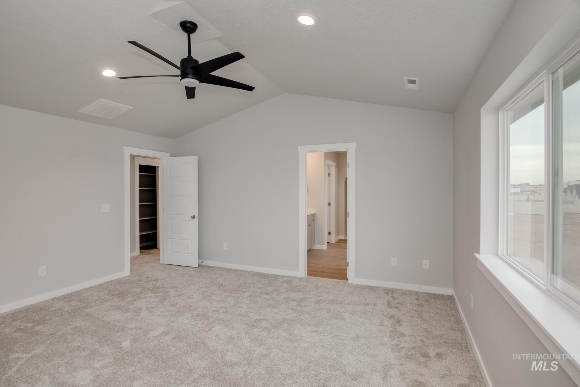 Unfurnished bedroom with lofted ceiling, light carpet, a ceiling fan, recessed lighting, and ensuite bath