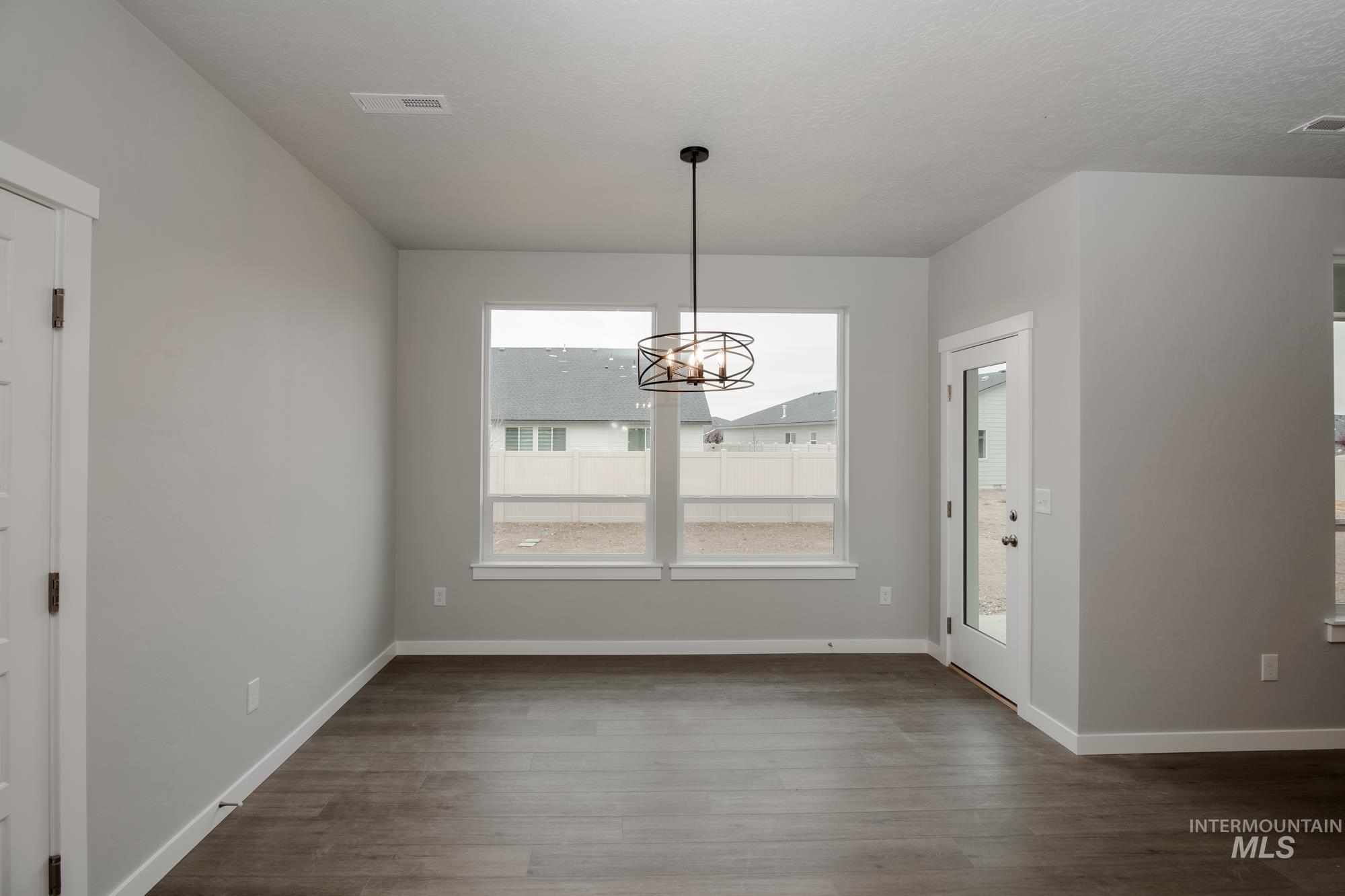 Unfurnished dining area featuring a chandelier and dark wood finished floors