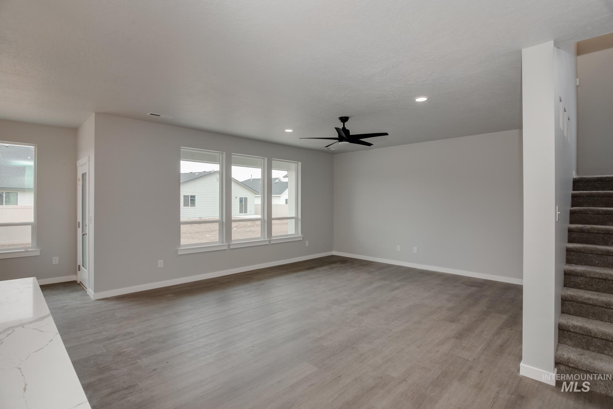 Unfurnished living room featuring stairway, light wood-style flooring, recessed lighting, and ceiling fan