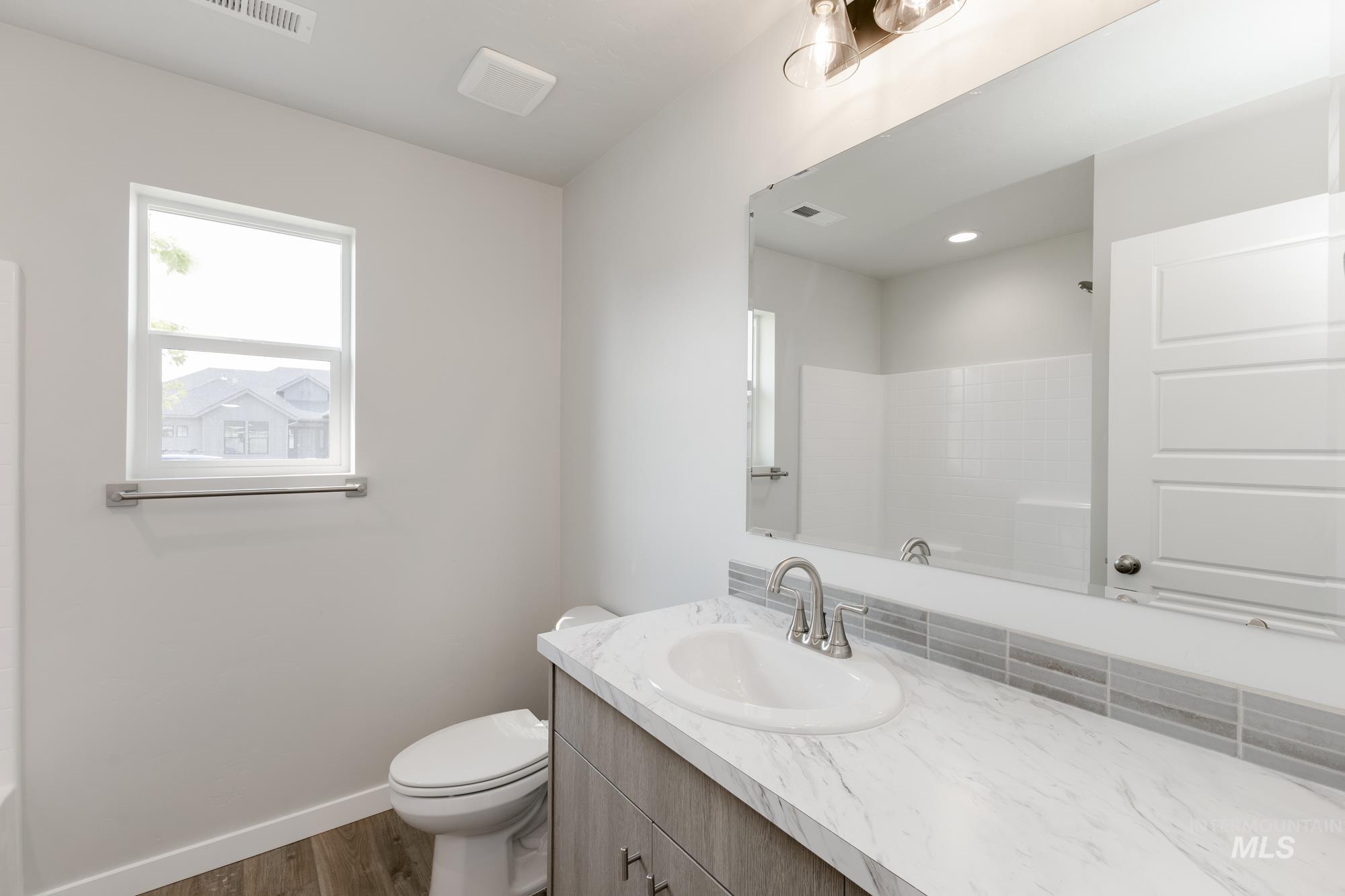 Bathroom with dark wood-style floors, vanity, and a shower