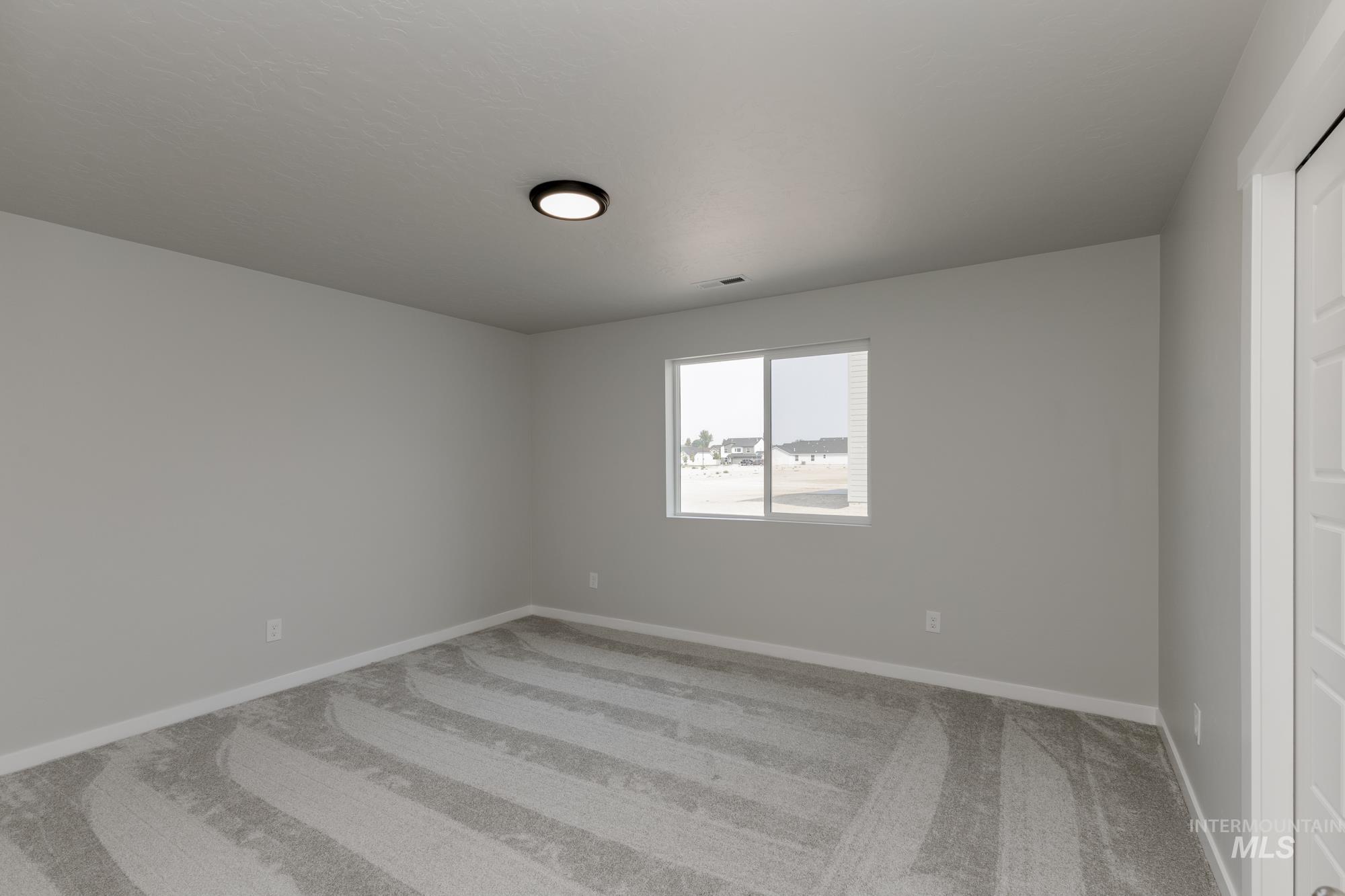 Spare room with light carpet and baseboards