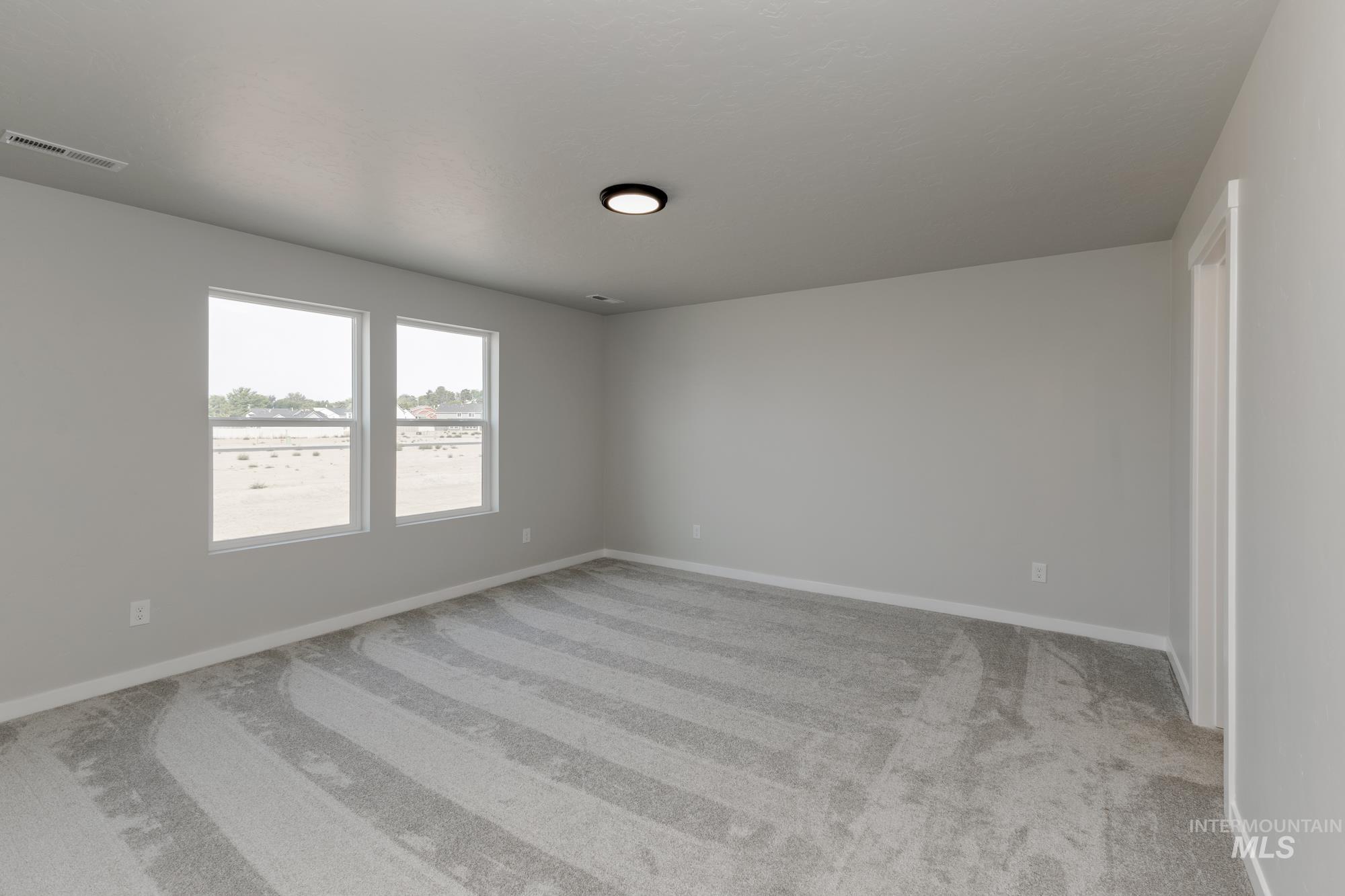 Unfurnished room featuring light carpet and baseboards