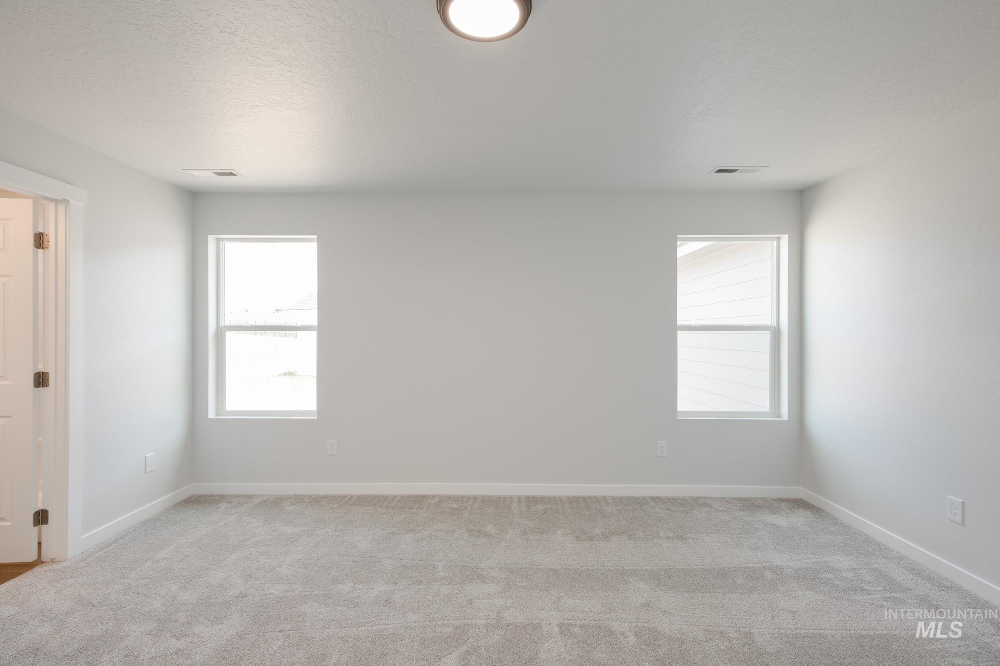Empty room featuring light colored carpet and a textured ceiling