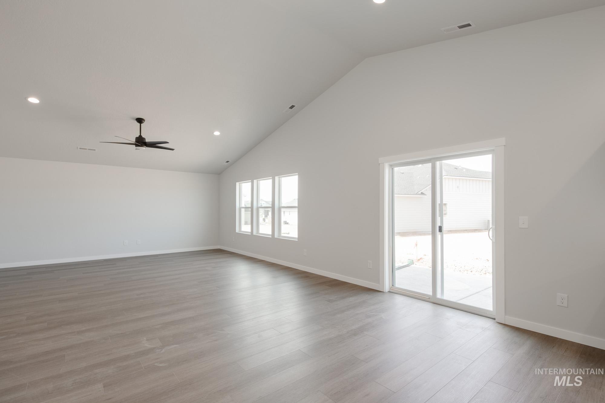 Unfurnished room with recessed lighting, healthy amount of natural light, light wood-style flooring, high vaulted ceiling, and ceiling fan